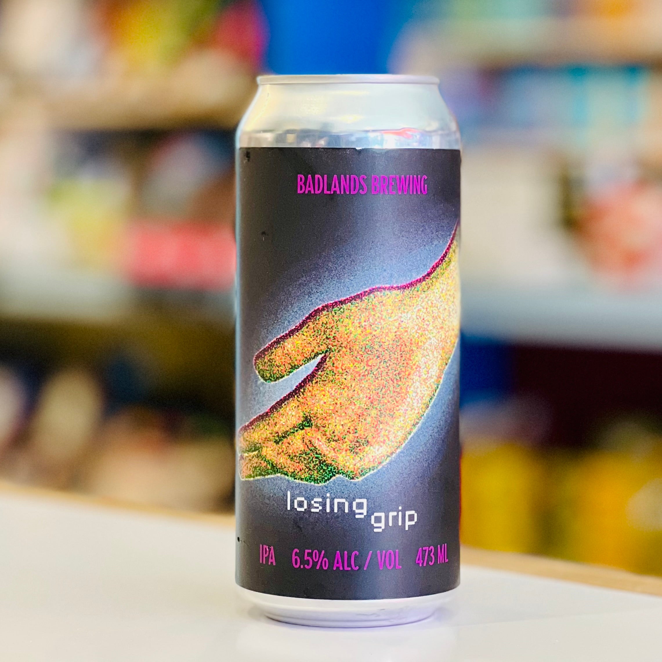 Beer can with 'Badlands Brewing' branding on a blurred store shelf background