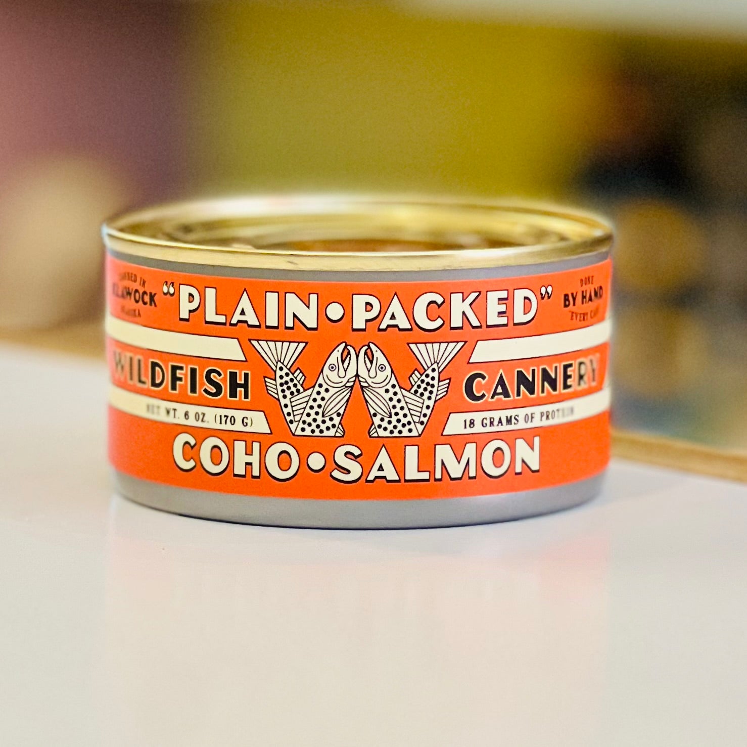 Canned coho salmon with an orange label on a white surface
