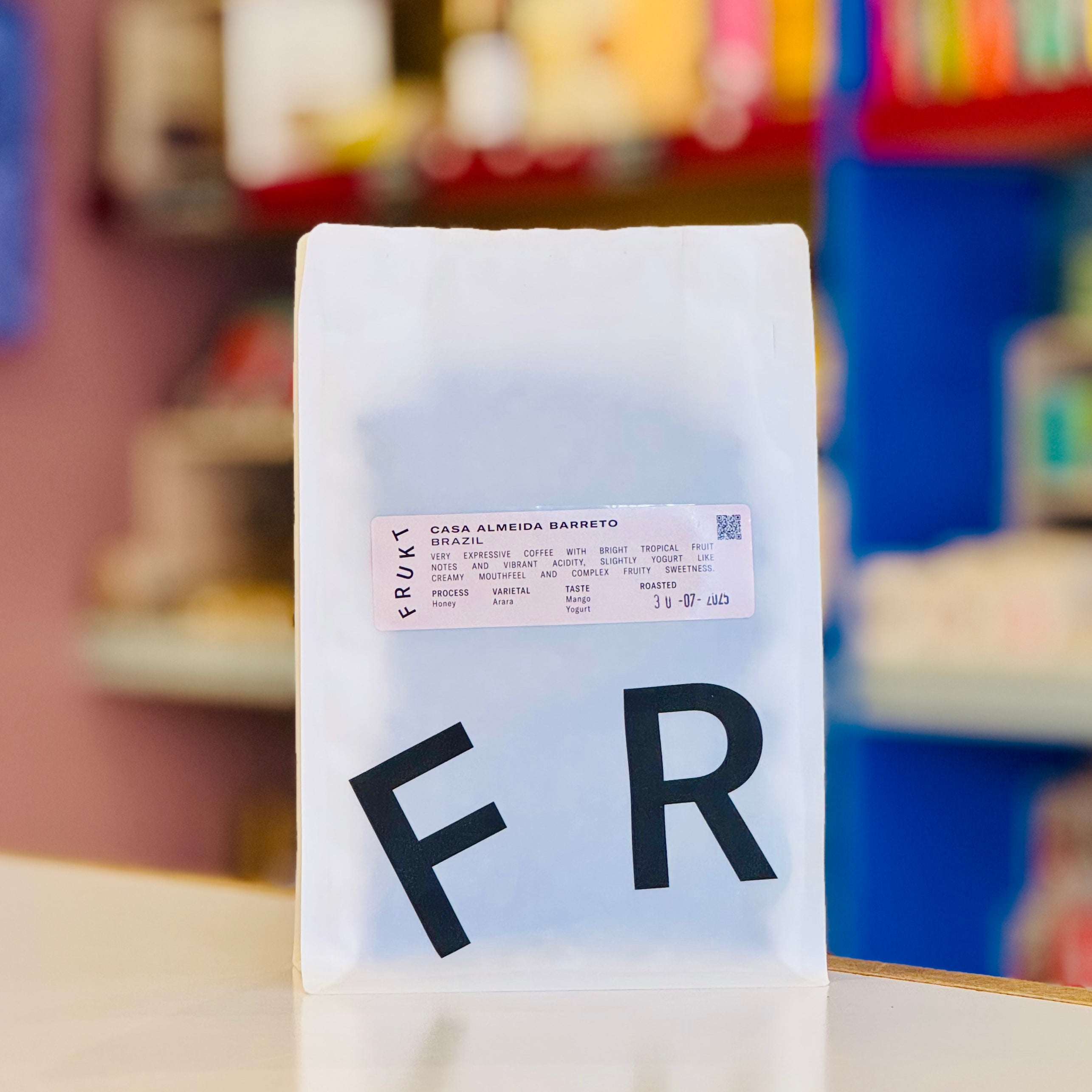 Coffee bag with 'FR' branding against a colorful blurred background