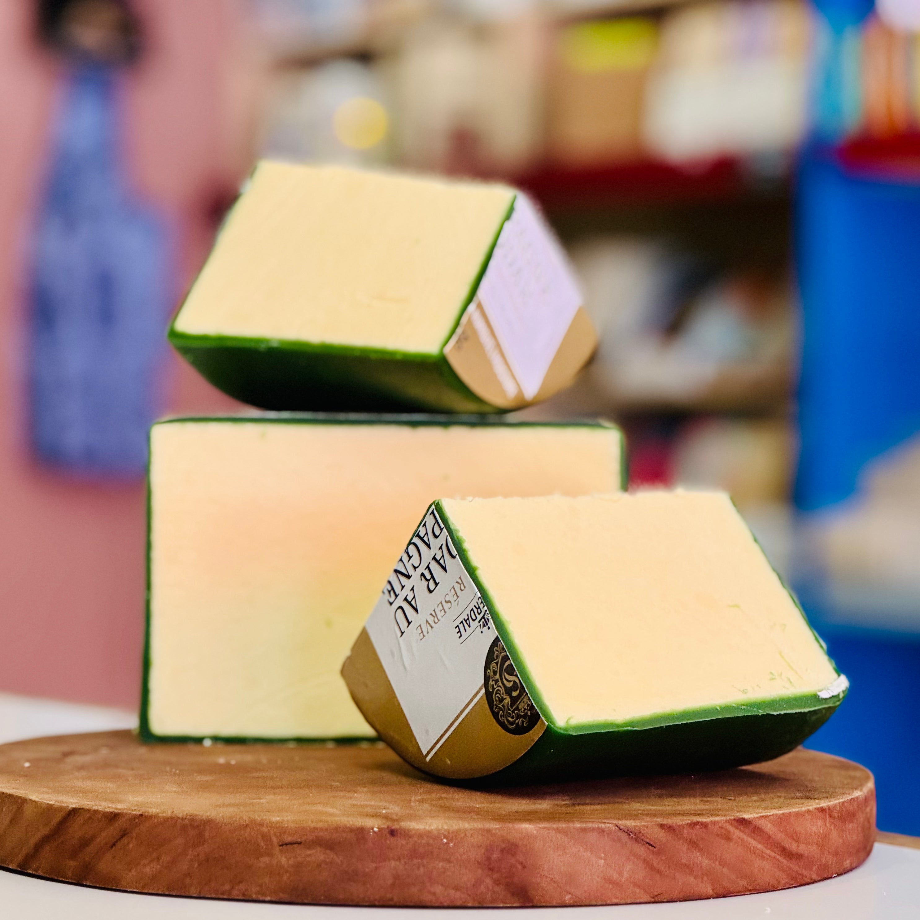 Three blocks of cheese on a wooden board with a blurred background
