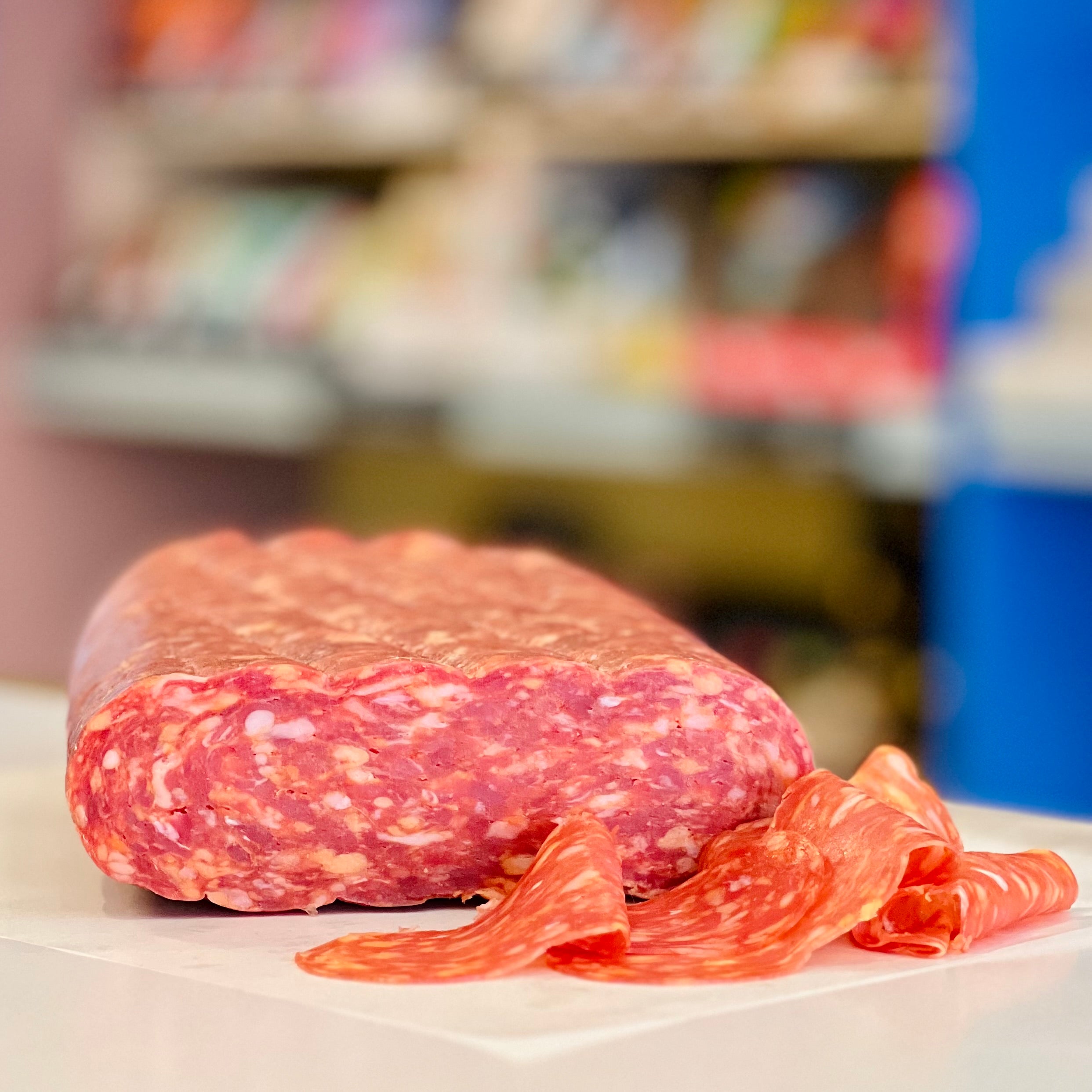 Cured Calabrese salami on a white surface with a blurred store background