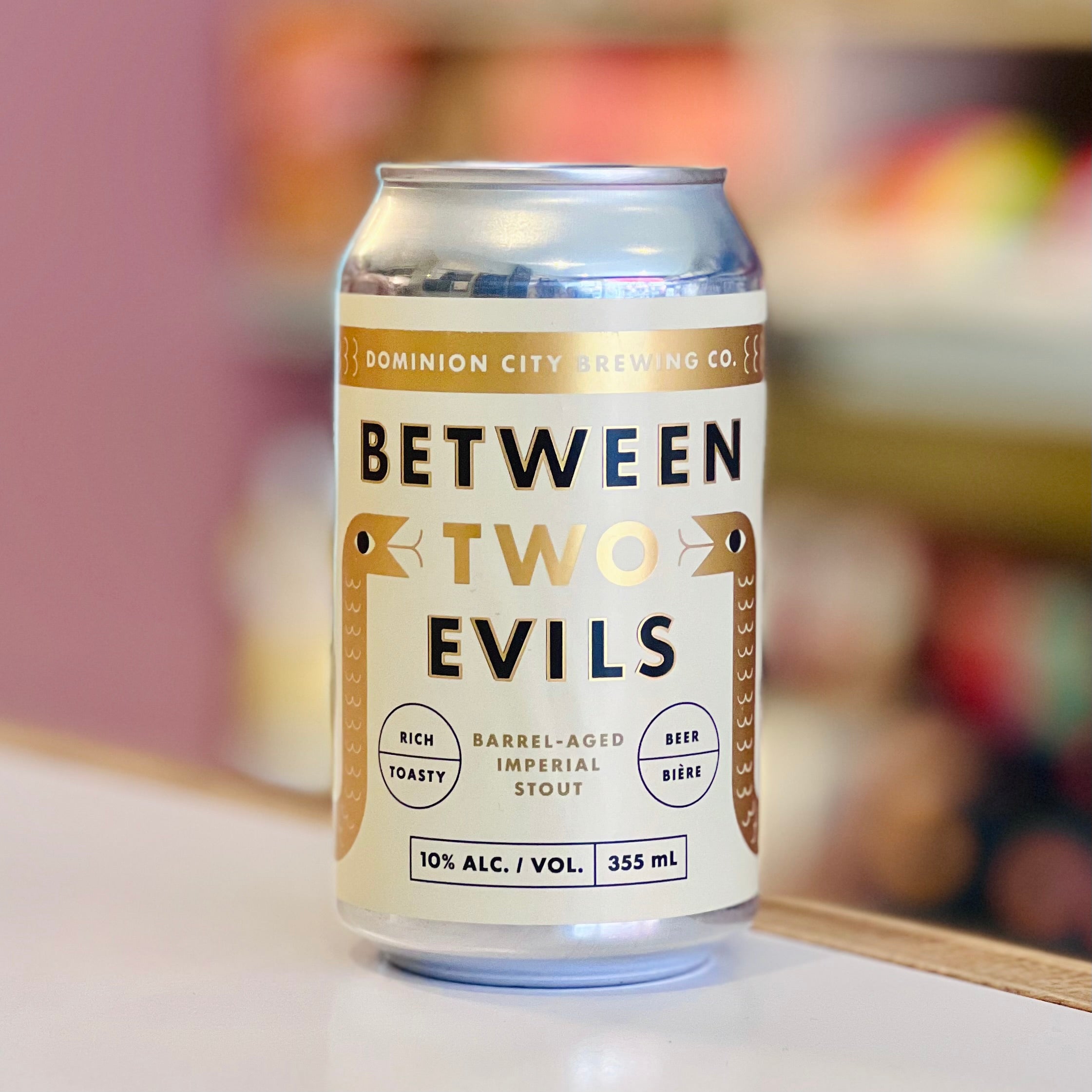 Can of 'Between Two Evils' stout beer from Dominion City Brewing Co. on a blurred background.