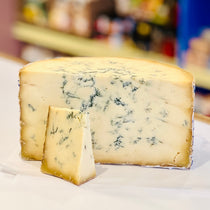 Blue cheese wedge with a smaller piece on a white surface, blurred background