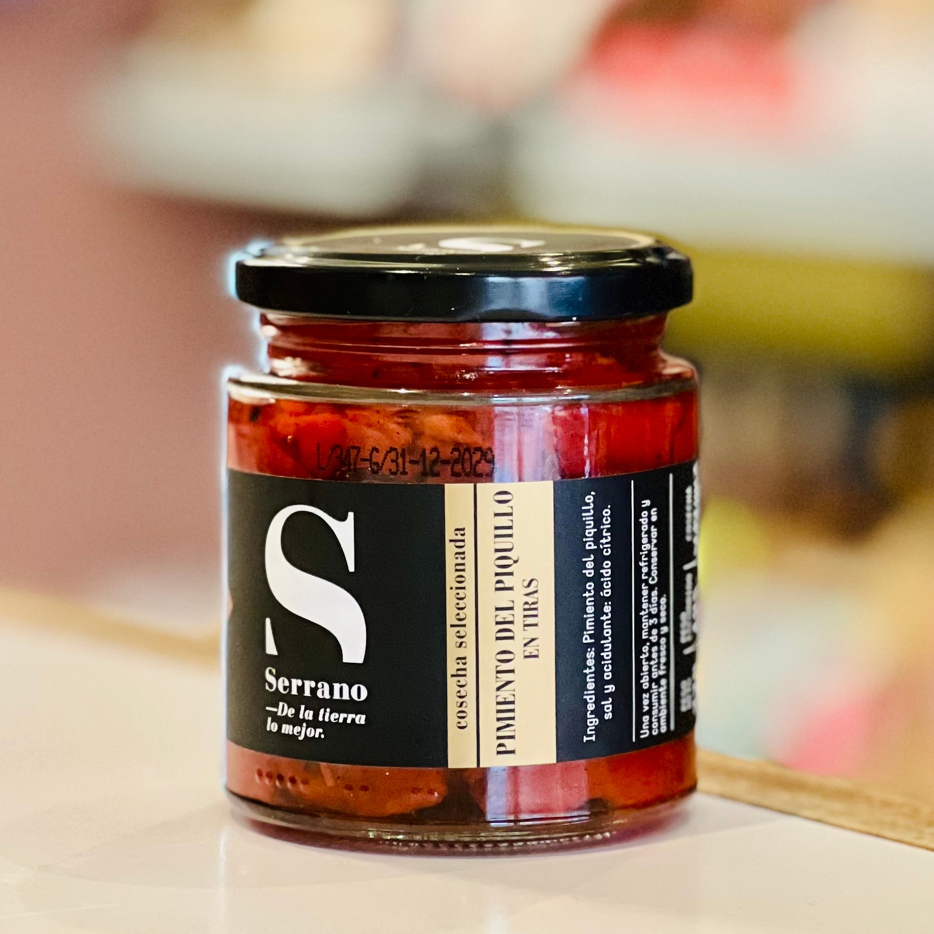 Jar of Piquillo peppers with a black label on a blurred background