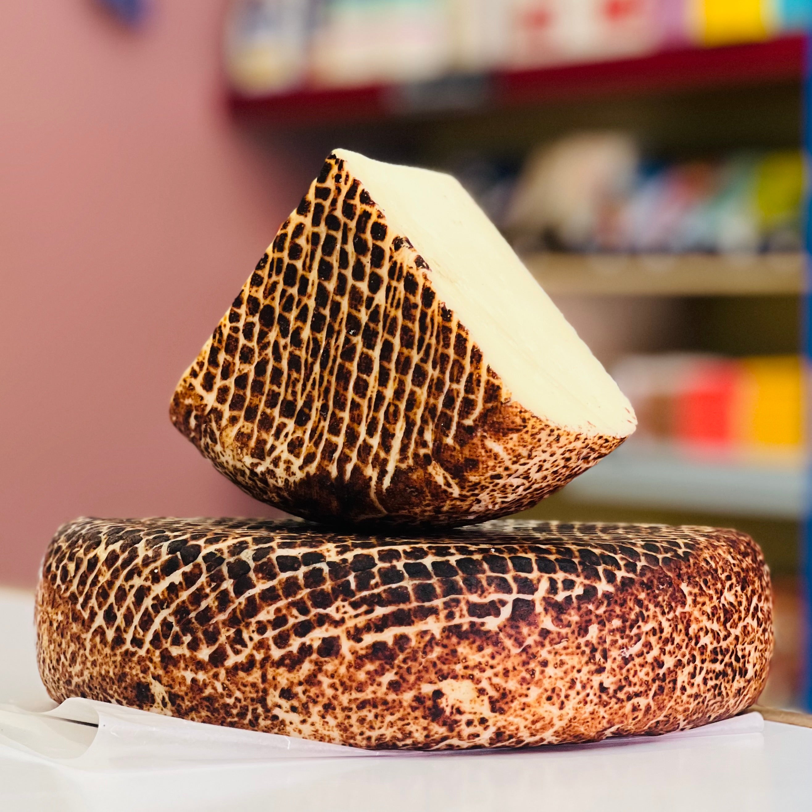 Two pieces of patterned cheese stacked on a table with a blurred background