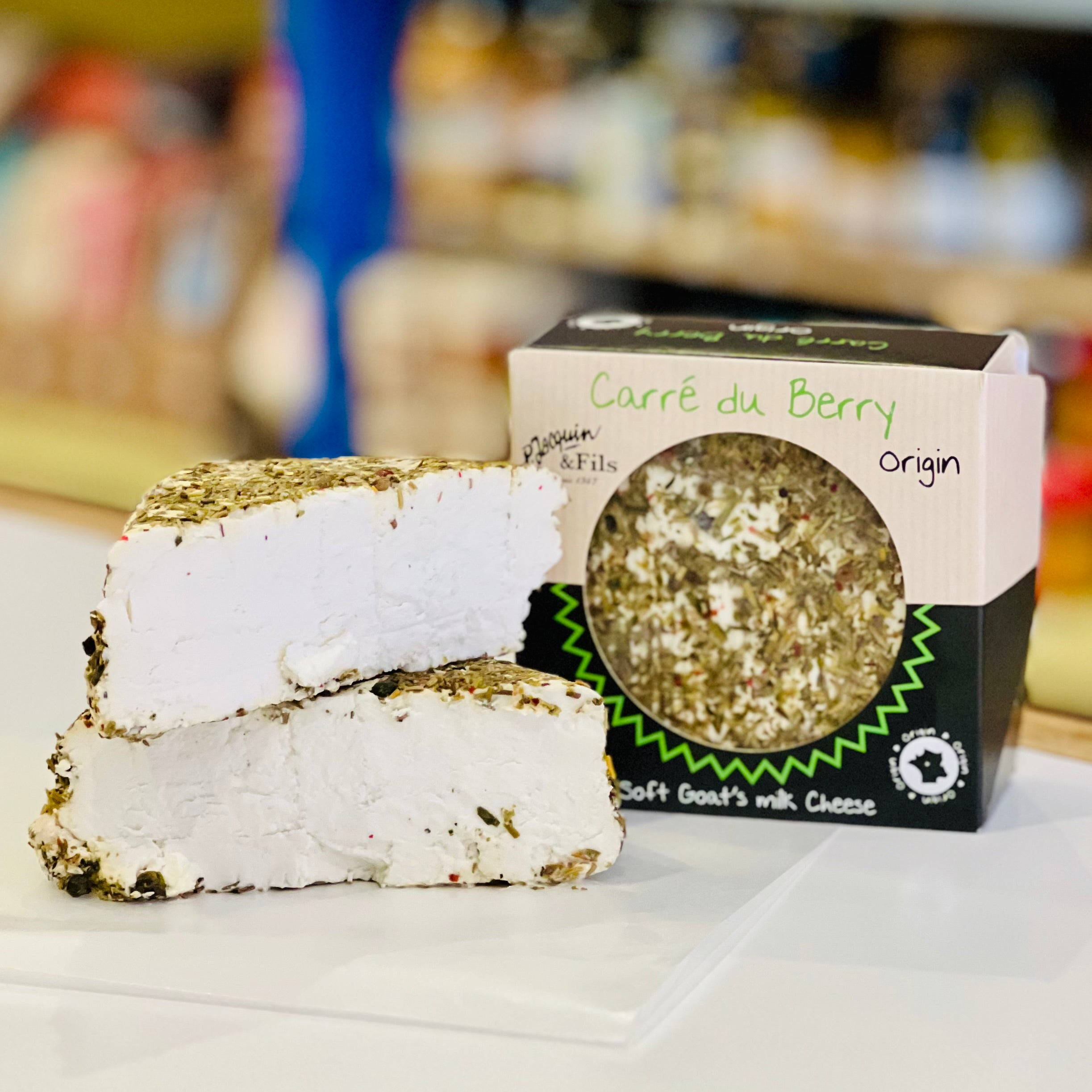Block of soft goat's milk cheese with 'Carré du Berry' packaging on a white surface.