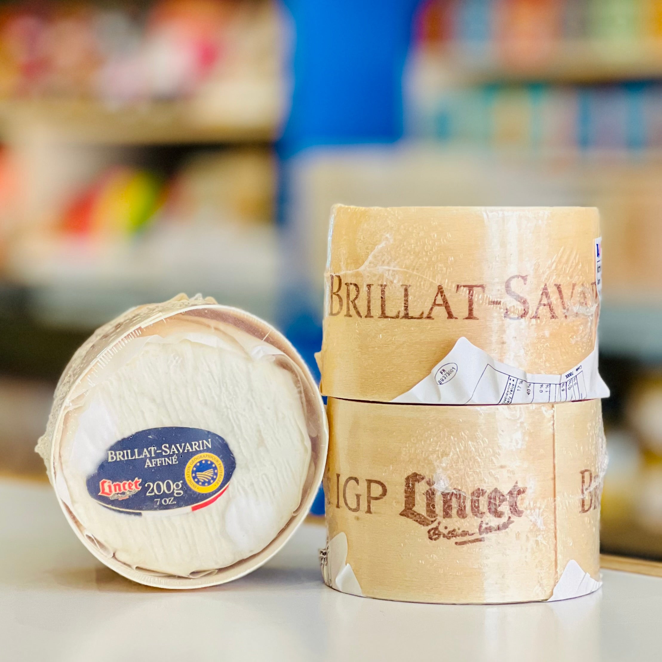 Two packages of Brillat-Savarin cheese with visible branding on a blurred background