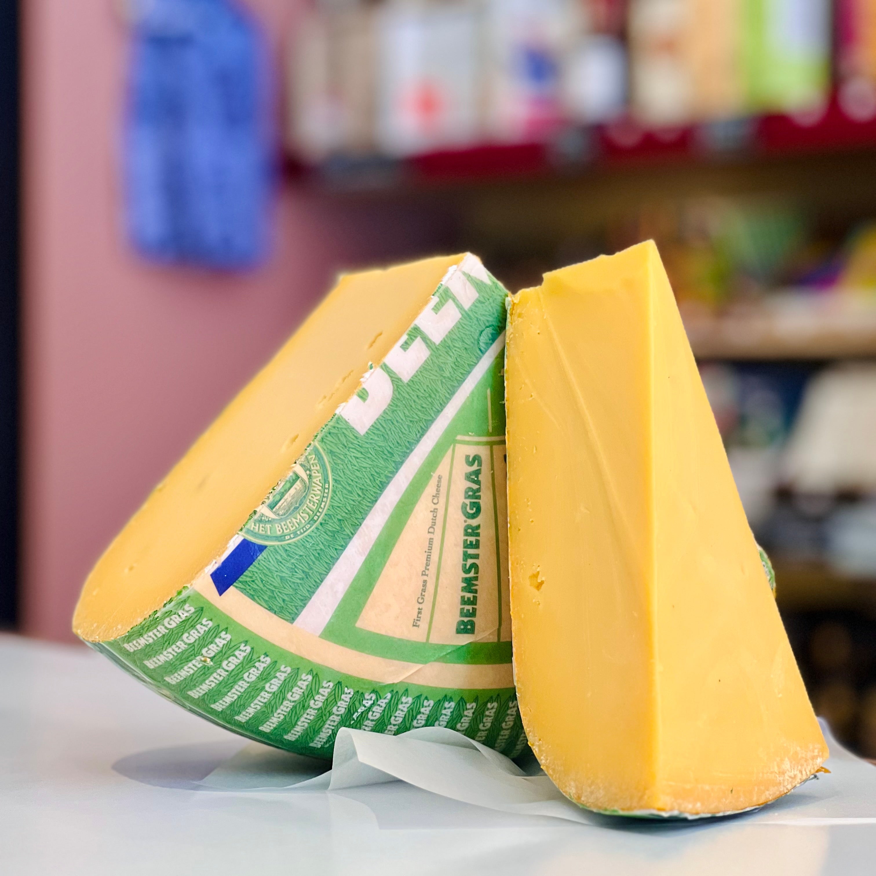 Two wedges of cheese with a green label on a white surface, blurred background