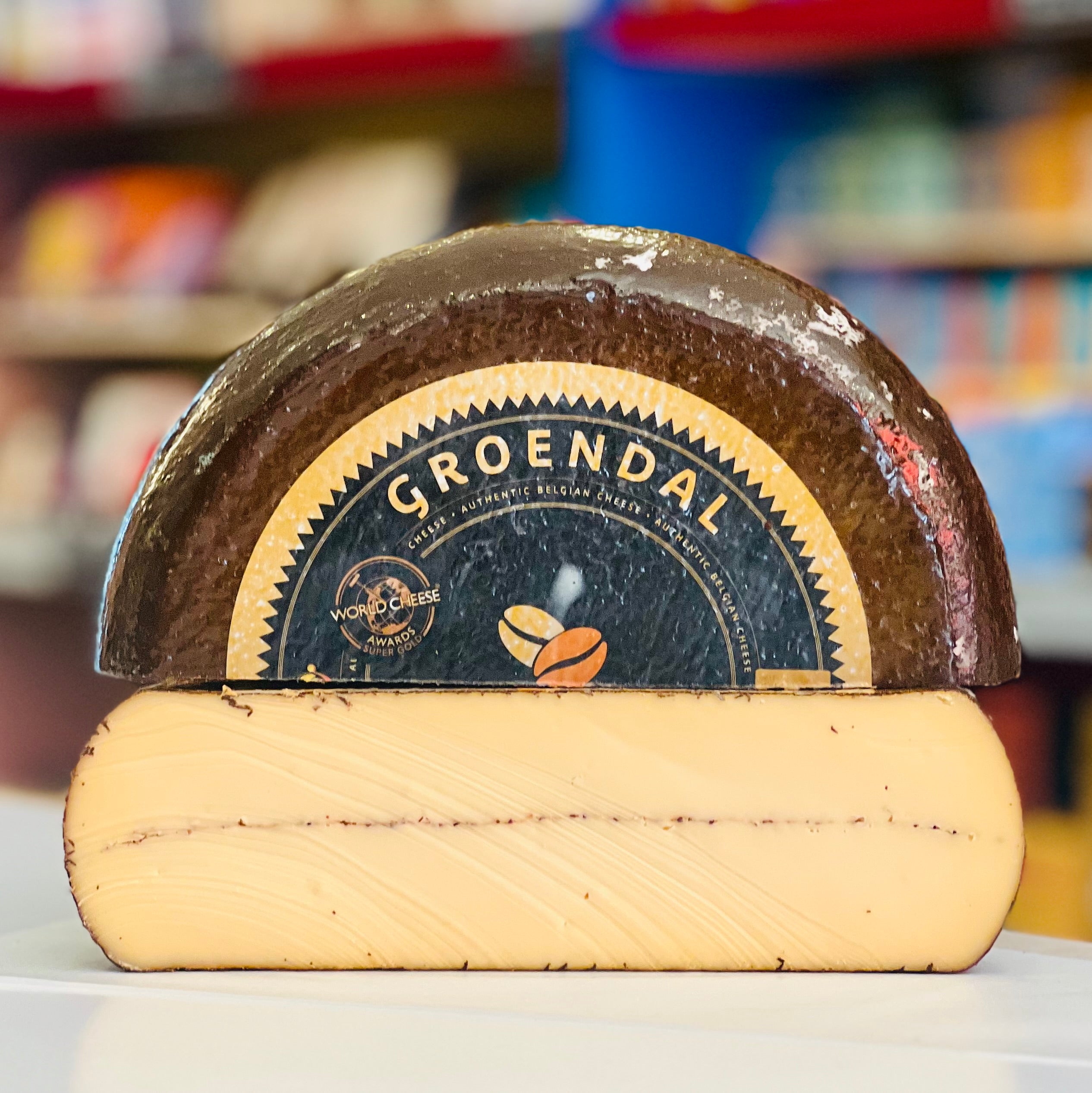 Half of a wheel of cheese with 'Groendal' branding on a blurred background