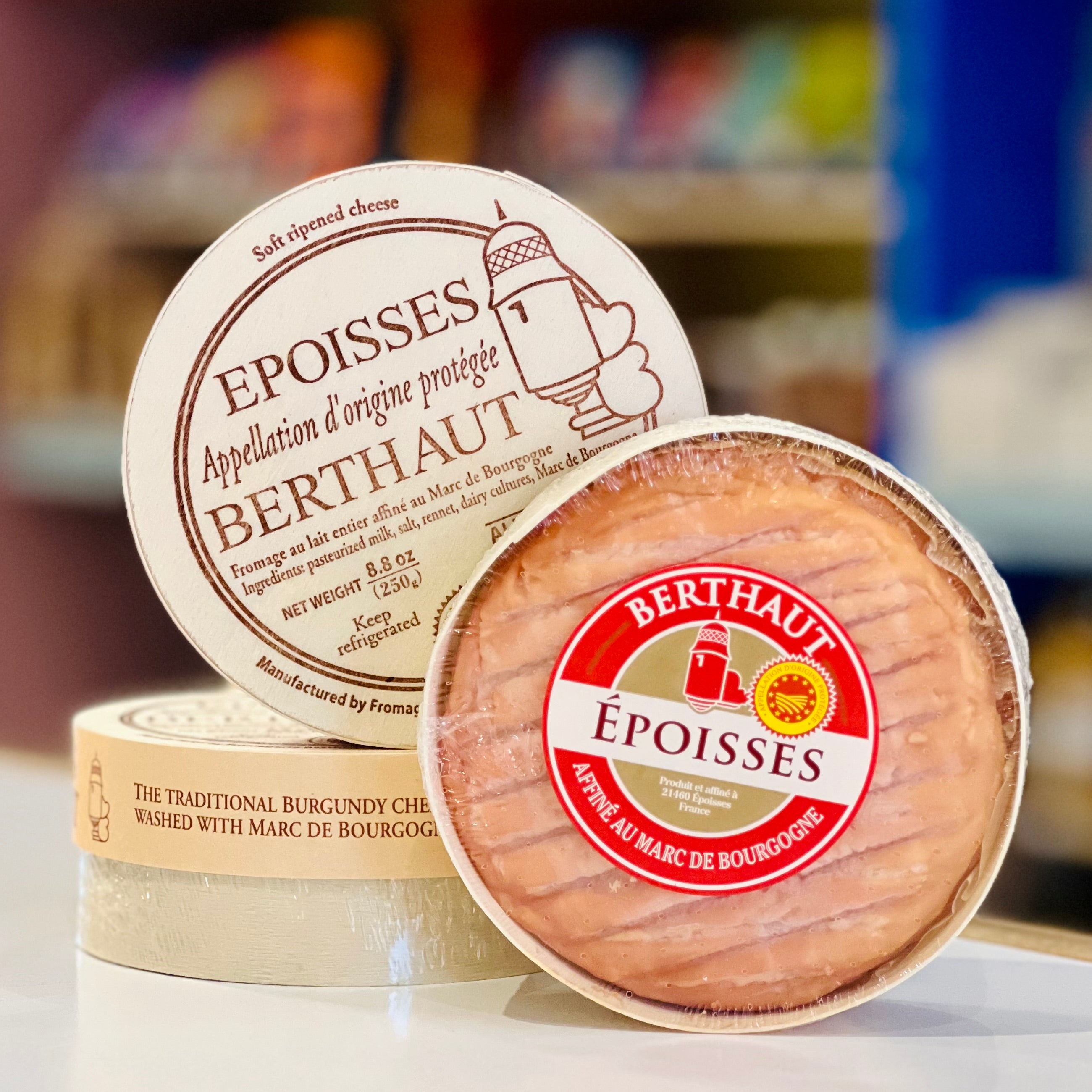 Two Epoisses cheeses with Berthaut branding on a blurred background