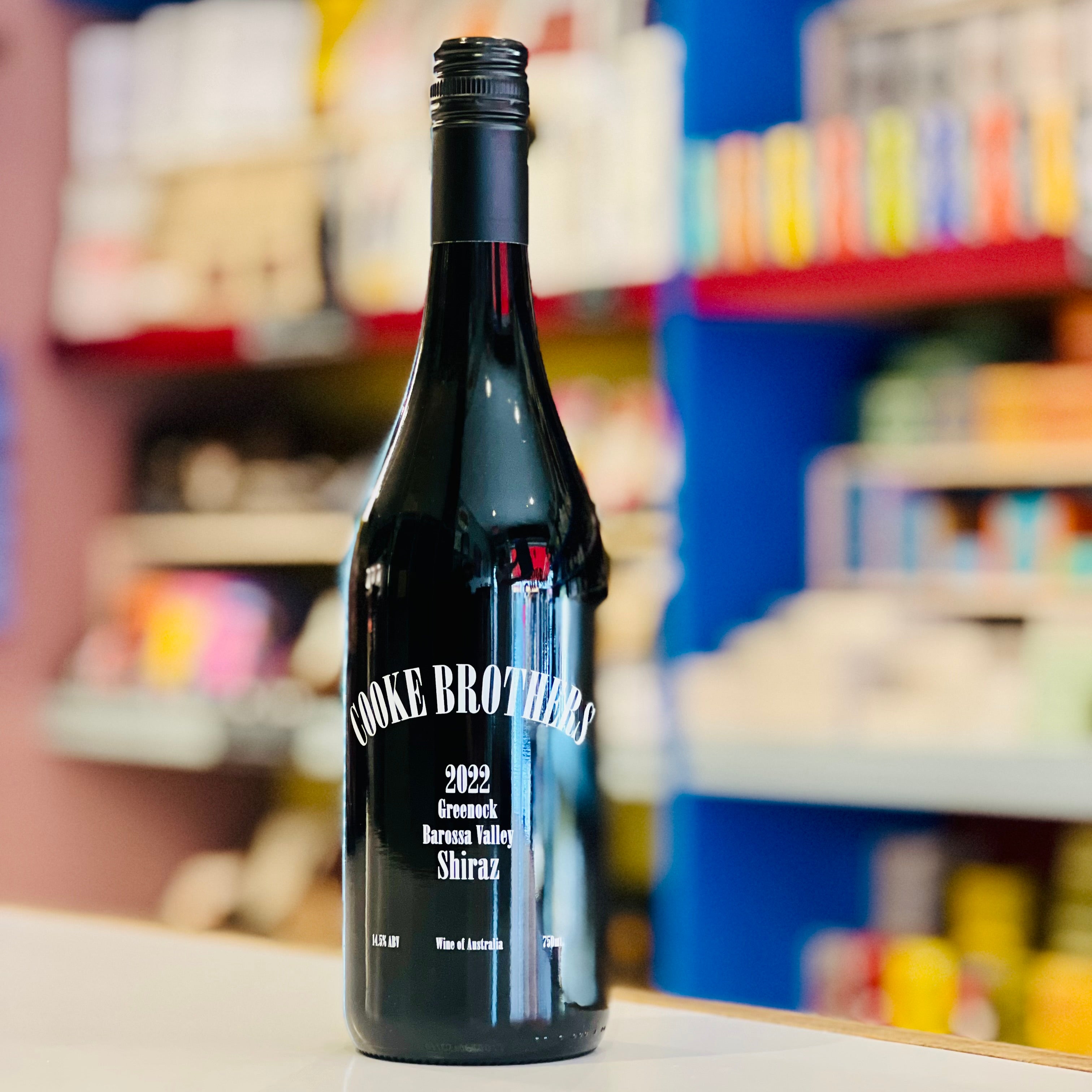 Wine bottle labeled 'Cooke Brothers' on a counter with a blurred store background
