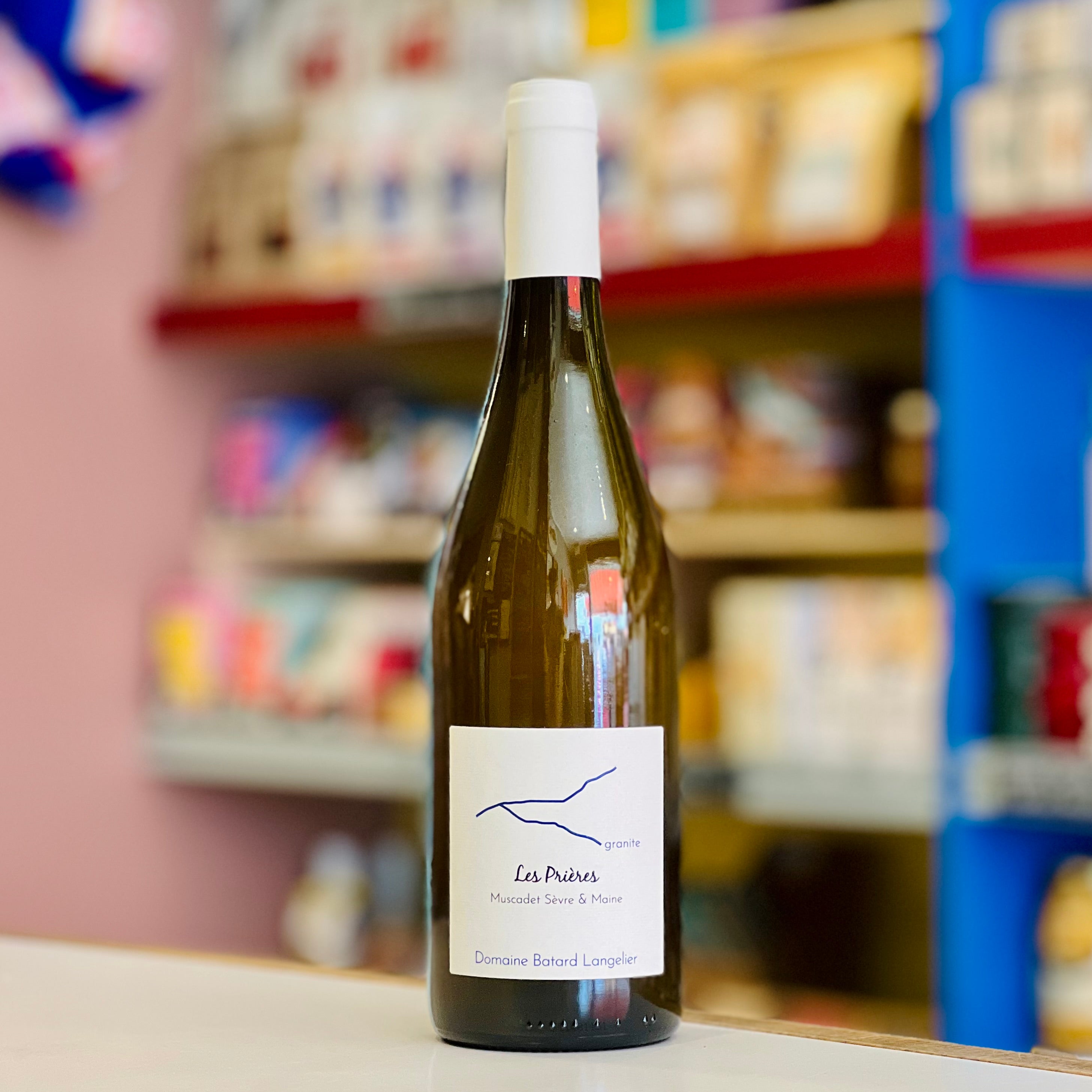 Wine bottle labeled 'Les Préries' on a shelf with blurred store background