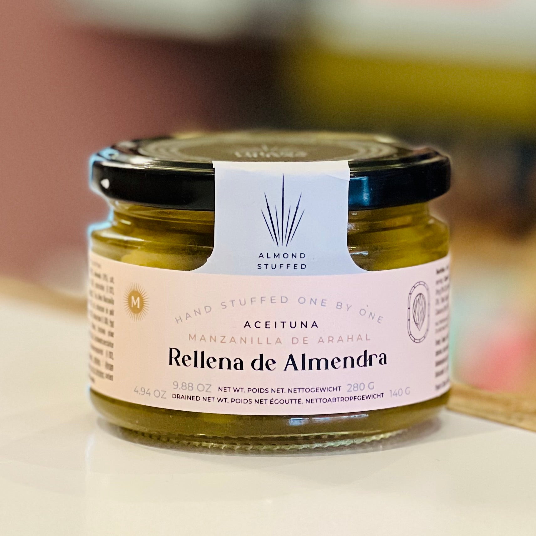 Jar of almond-stuffed olives with a visible label on a blurred background