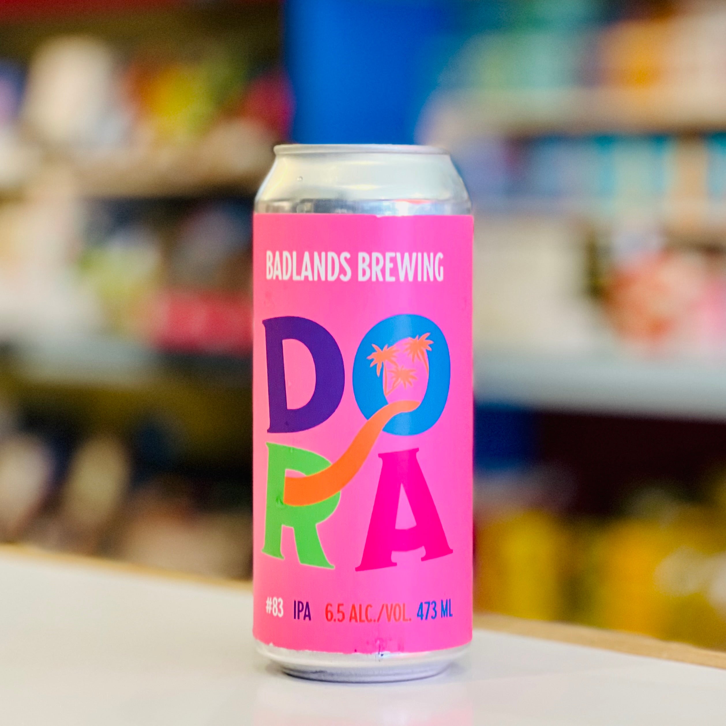 Pink can of Badlands Brewing Dora IPA with a blurred store shelf in the background