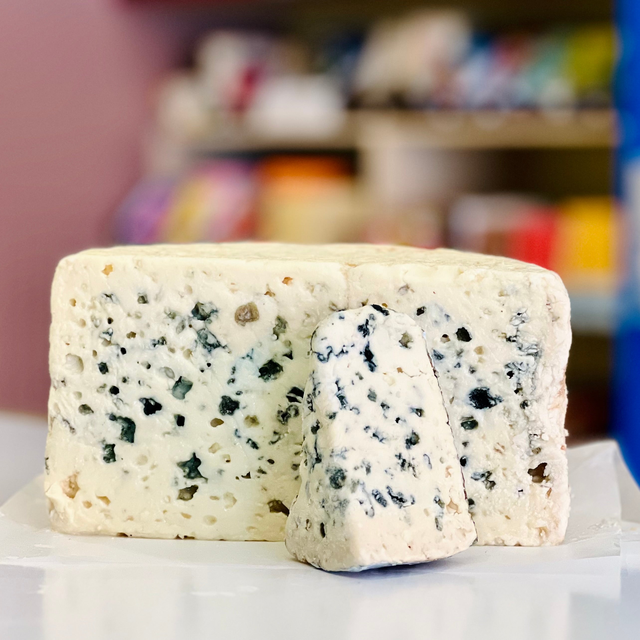 Blue cheese wedge on a white surface with a blurred background