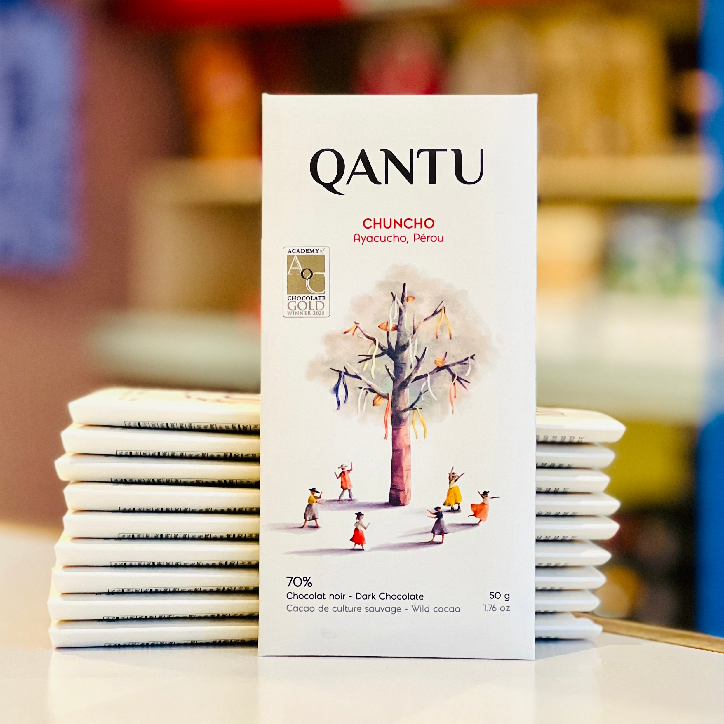 QANTU Chuncho chocolate bar packaging with a stack of bars on a blurred background