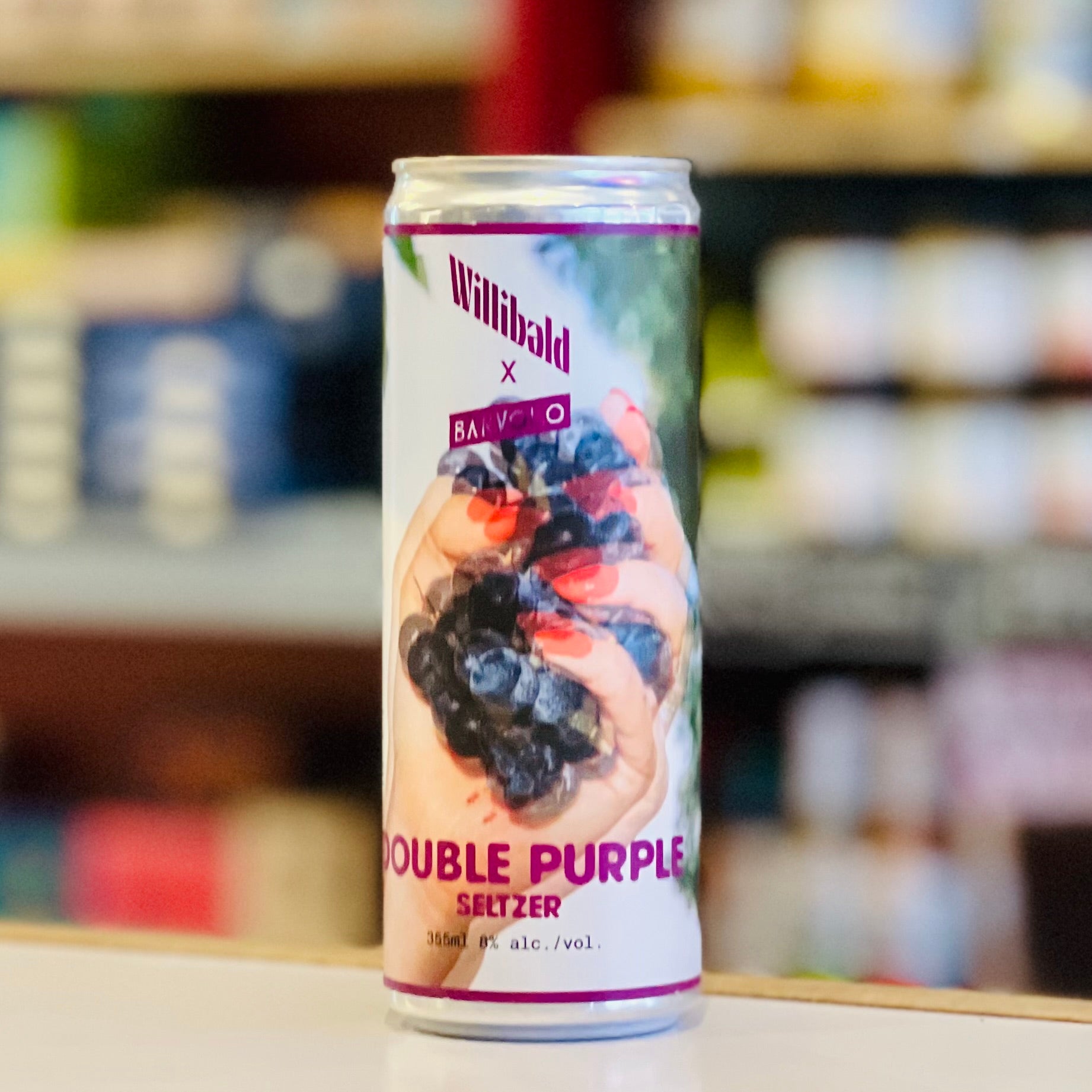 Willibald Double Purple Seltzer can with berry design on a blurred store shelf background