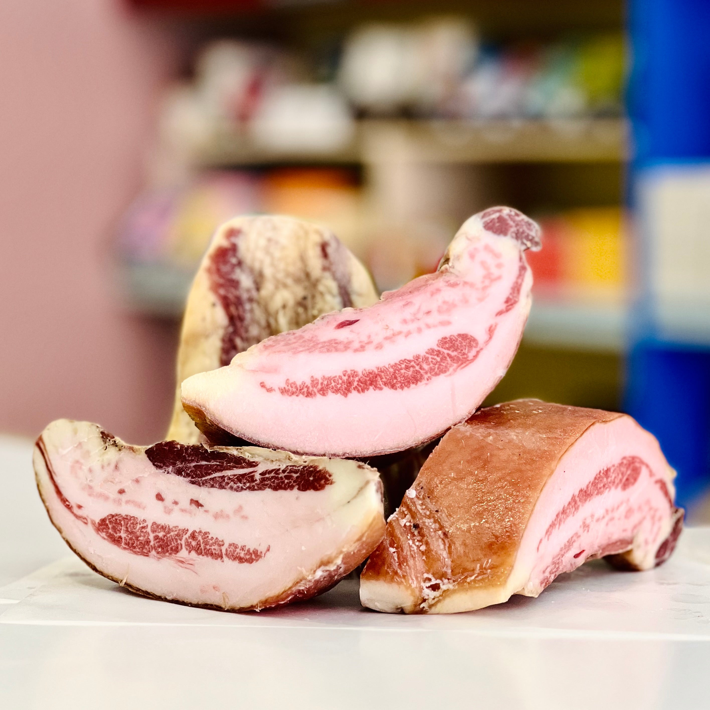 Sliced guanciale chunks on a white surface with a blurred background