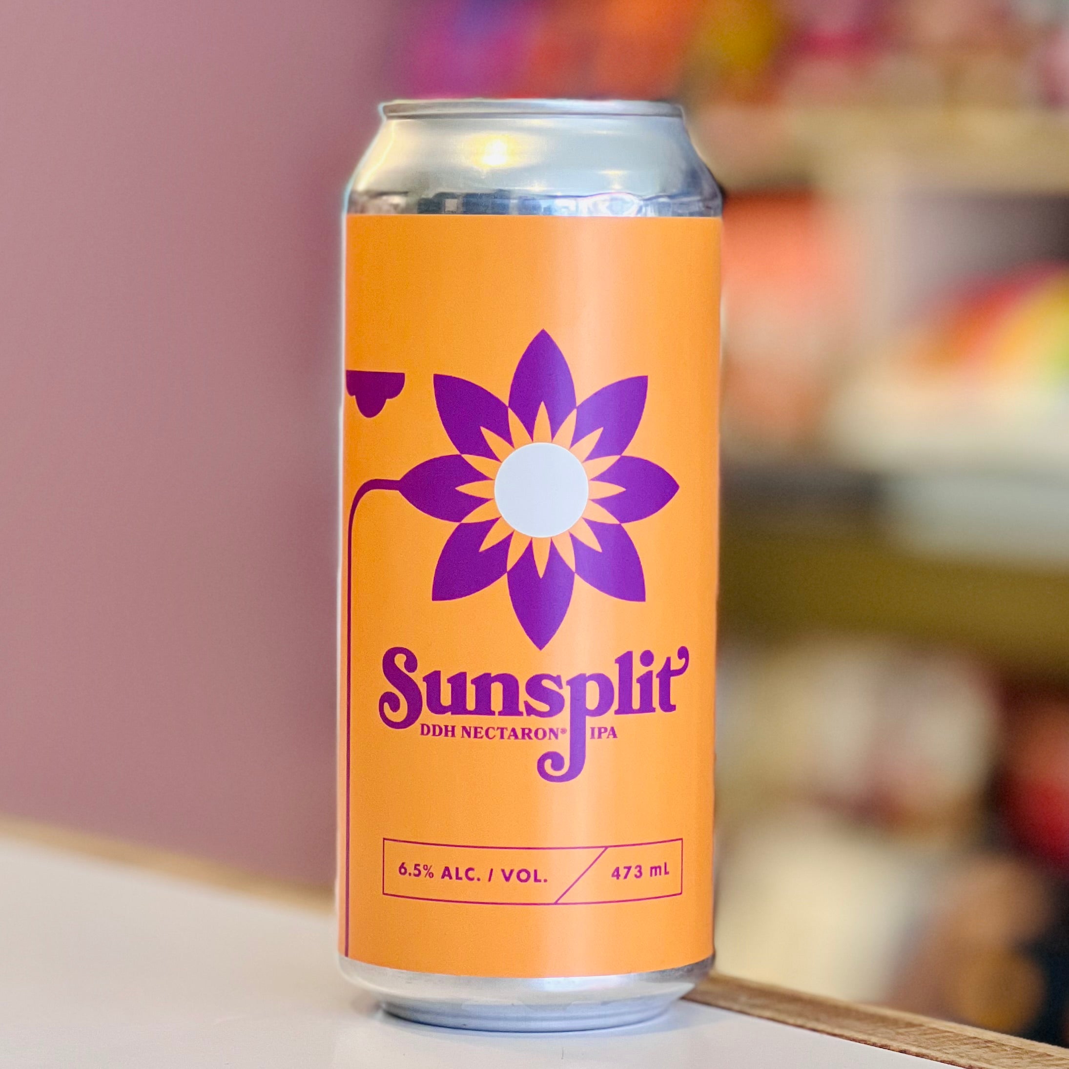 Orange can with purple flower design and 'Sunsplit' branding on a blurred background