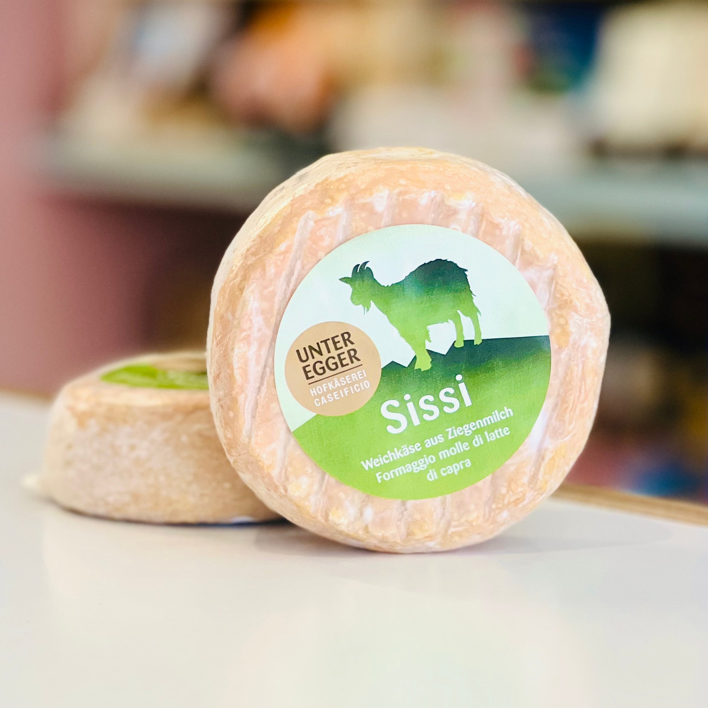 Two wheels of cheese with 'Unter Egger' label on a blurred background