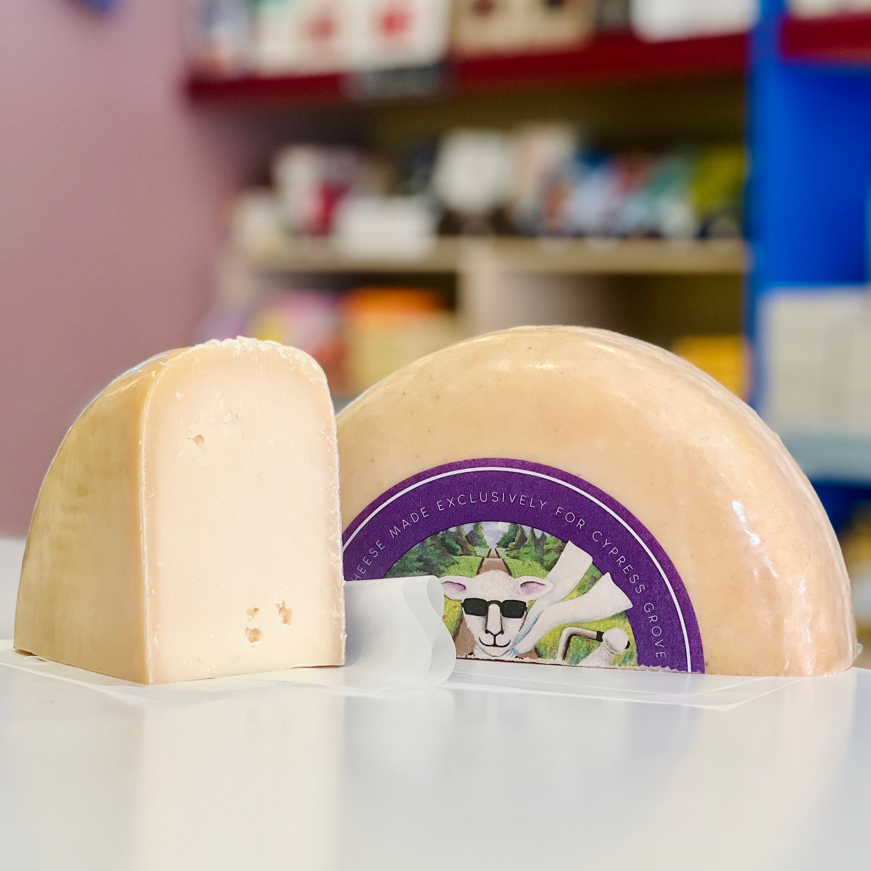 Two wheels of cheese with a branded label on a counter in a store setting.