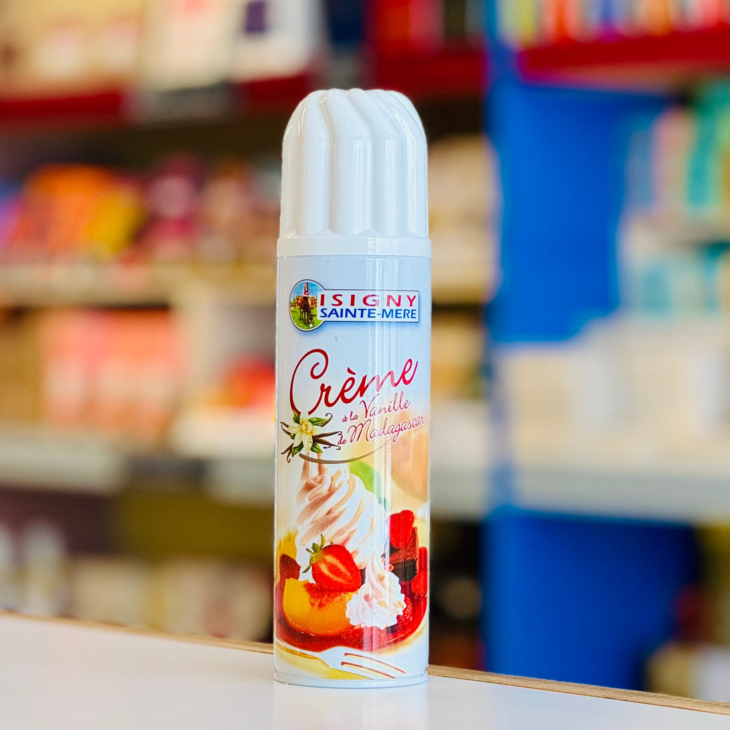 Spray can with 'Lesigny Sainte-Mere' branding on a blurred store shelf background