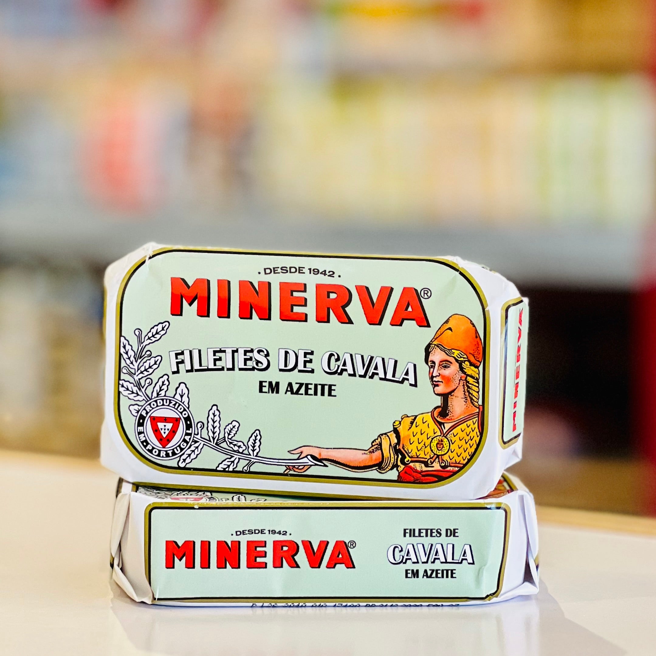 Two Minerva Filetes de Cavaia em Azeite (minced caviar in olive oil) packages stacked on a light-colored counter with a blurred supermarket background.