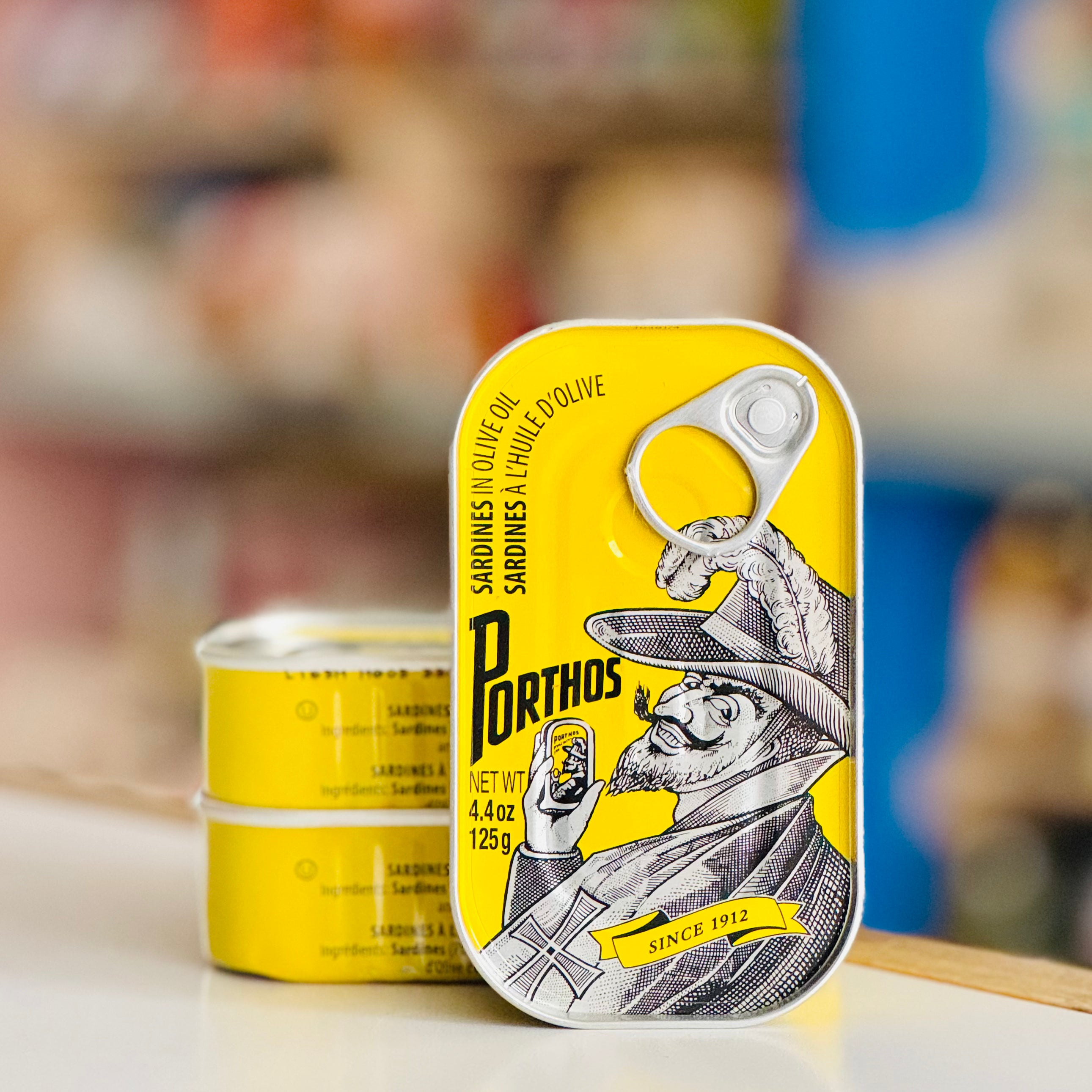 Two cans of Dorthos sardines with a prominent yellow label featuring a graphic design.