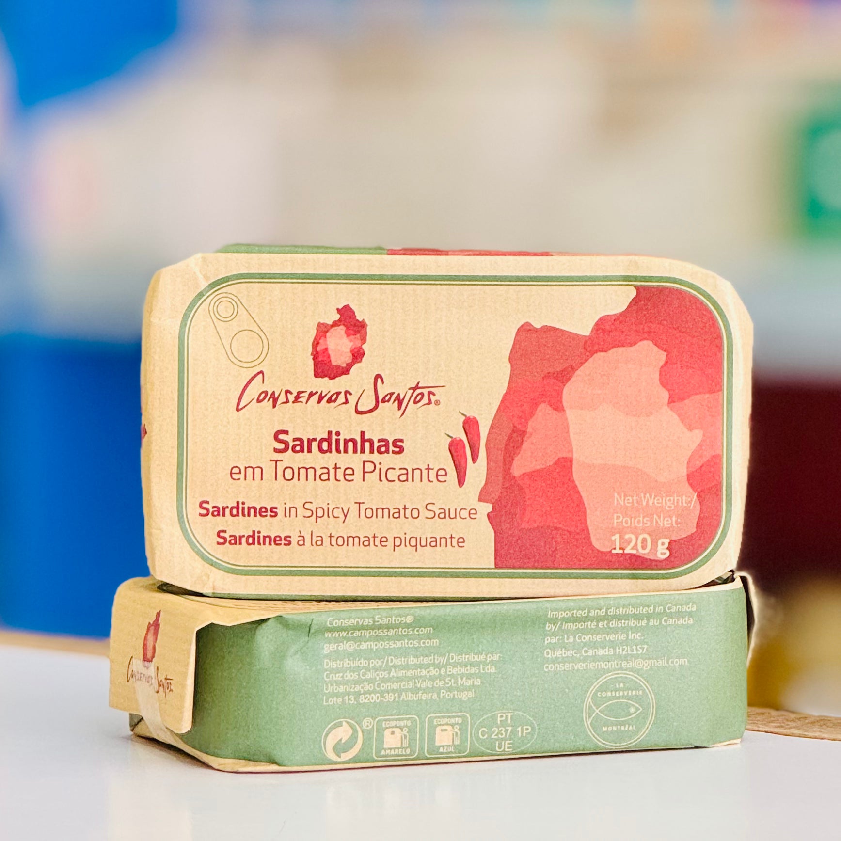 Two tins of Conservas Santos Sardines in Spicy Tomato Sauce on a white surface with a blurred background.