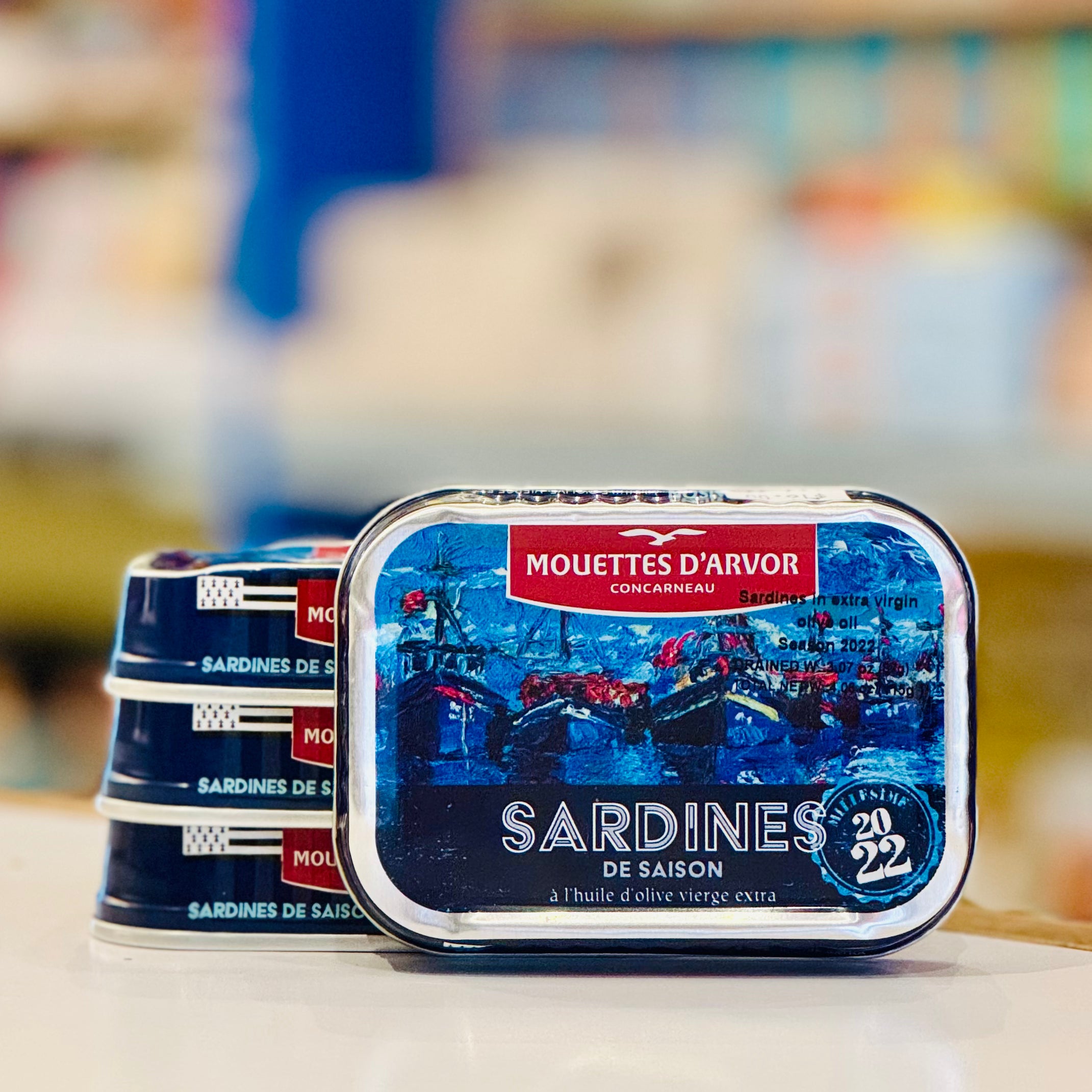Tins of Mouettes d'Arvor sardines on a shelf with a blurred background