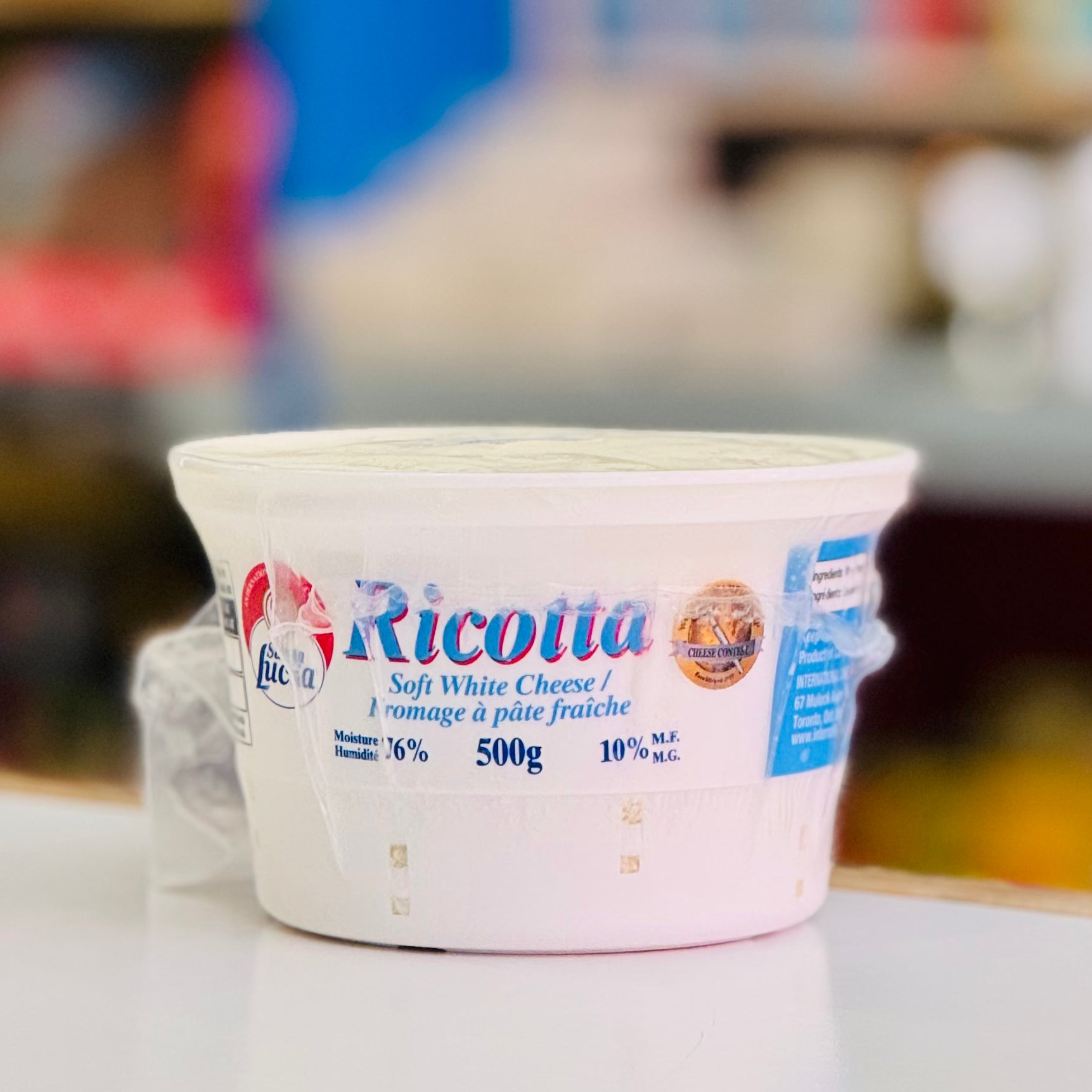 Container of Ricotta cheese with a blurred background