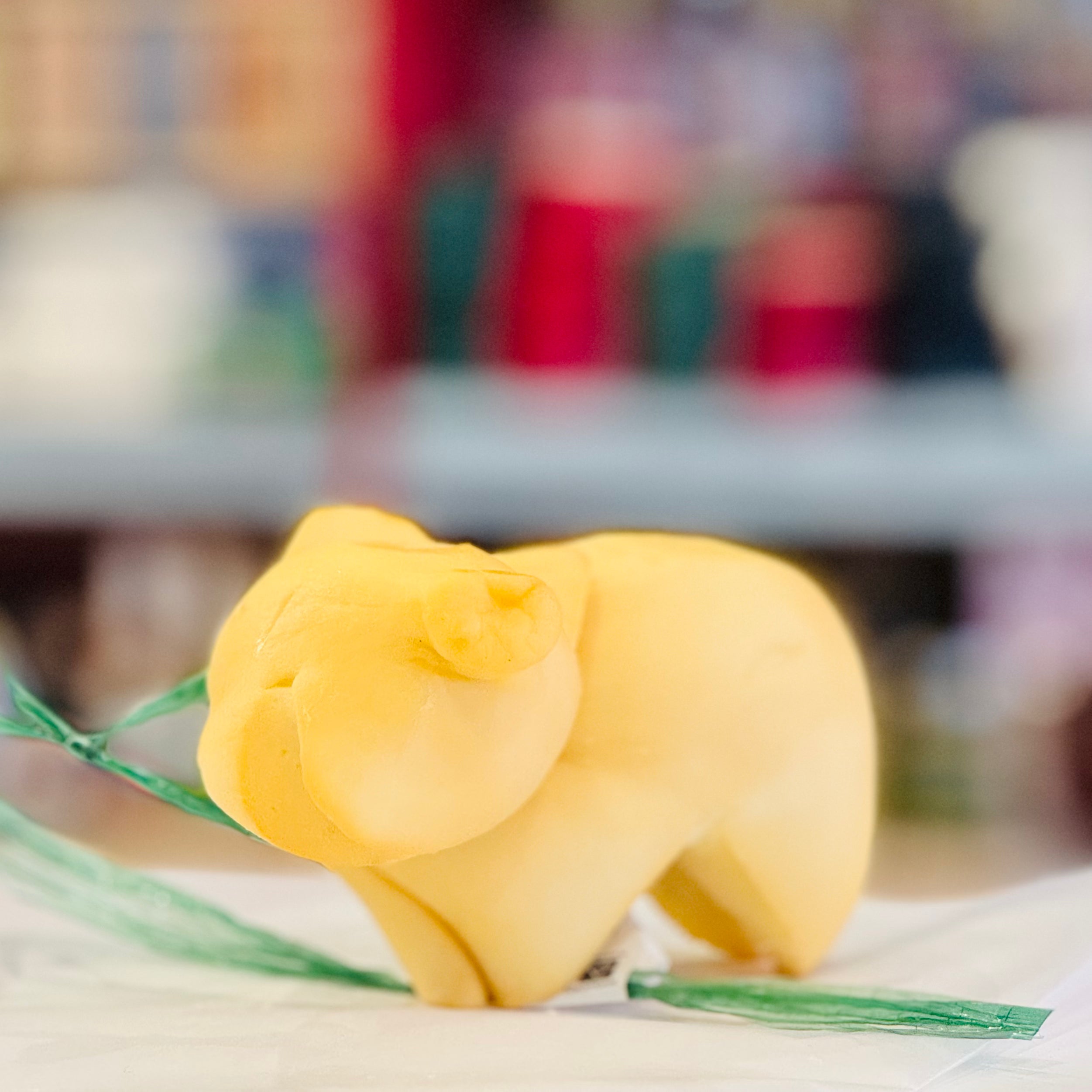 Yellow pig-shaped cheese on a white surface with a blurred background
