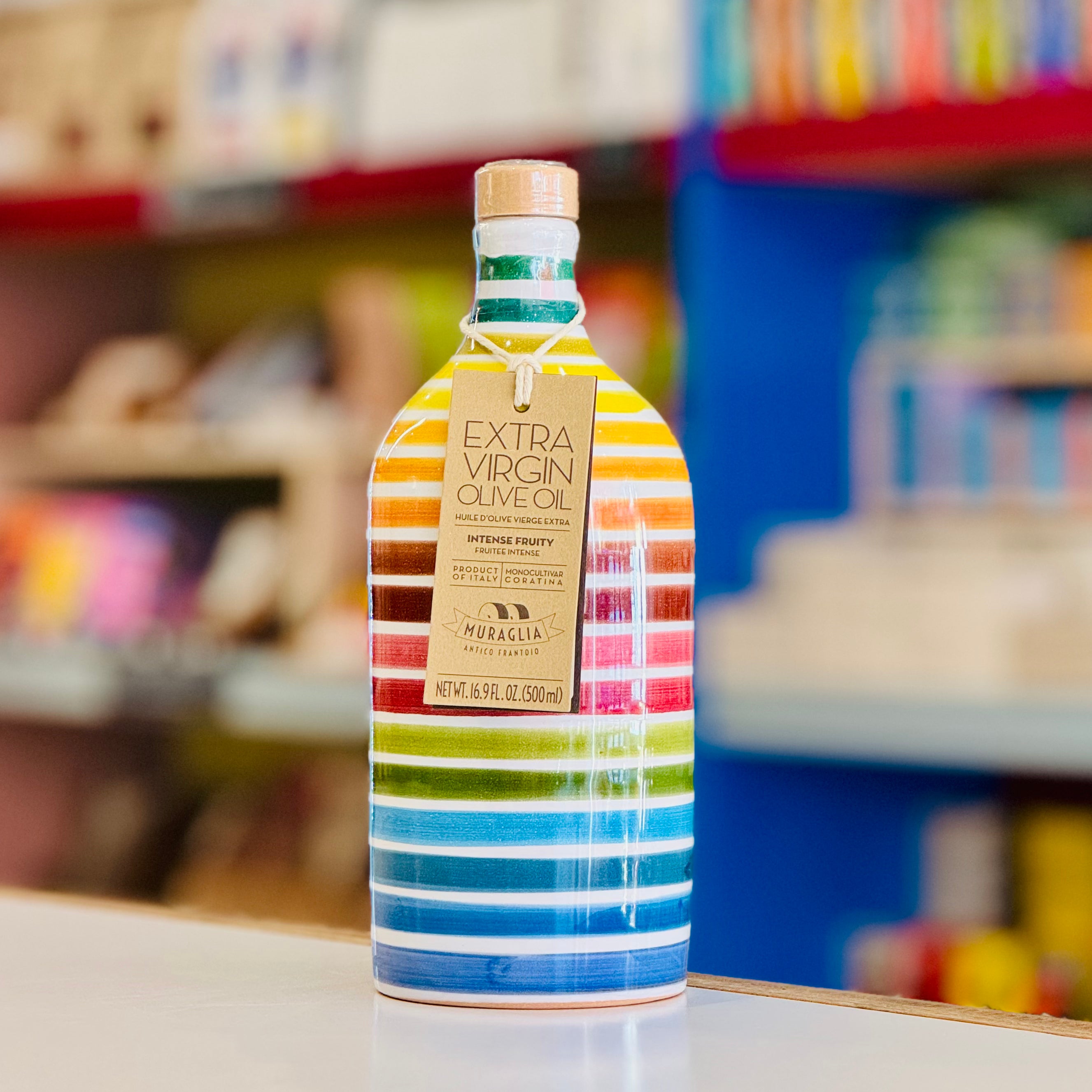 Bottle of extra virgin olive oil with colorful stripes on a shelf.