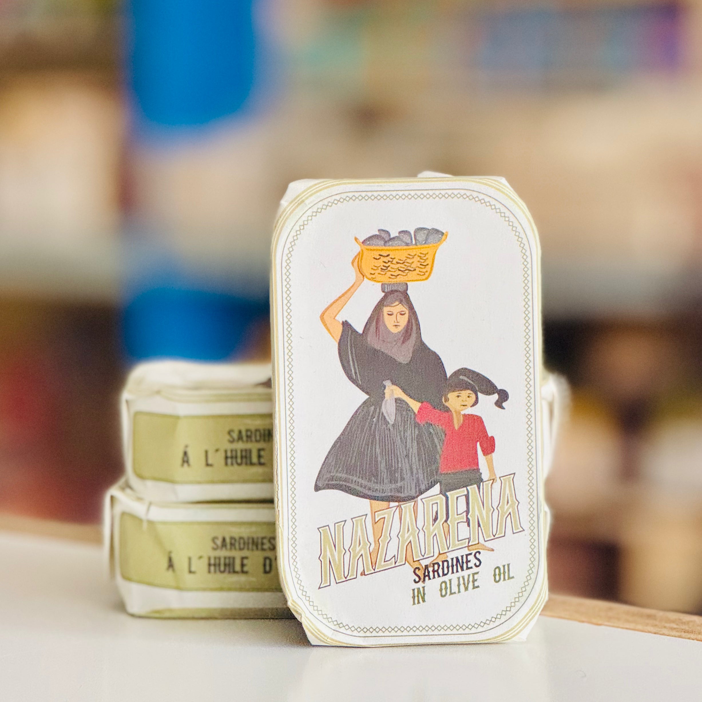 Vintage-style 'Nazarena' sardine can with a woman and child illustration on a blurred background