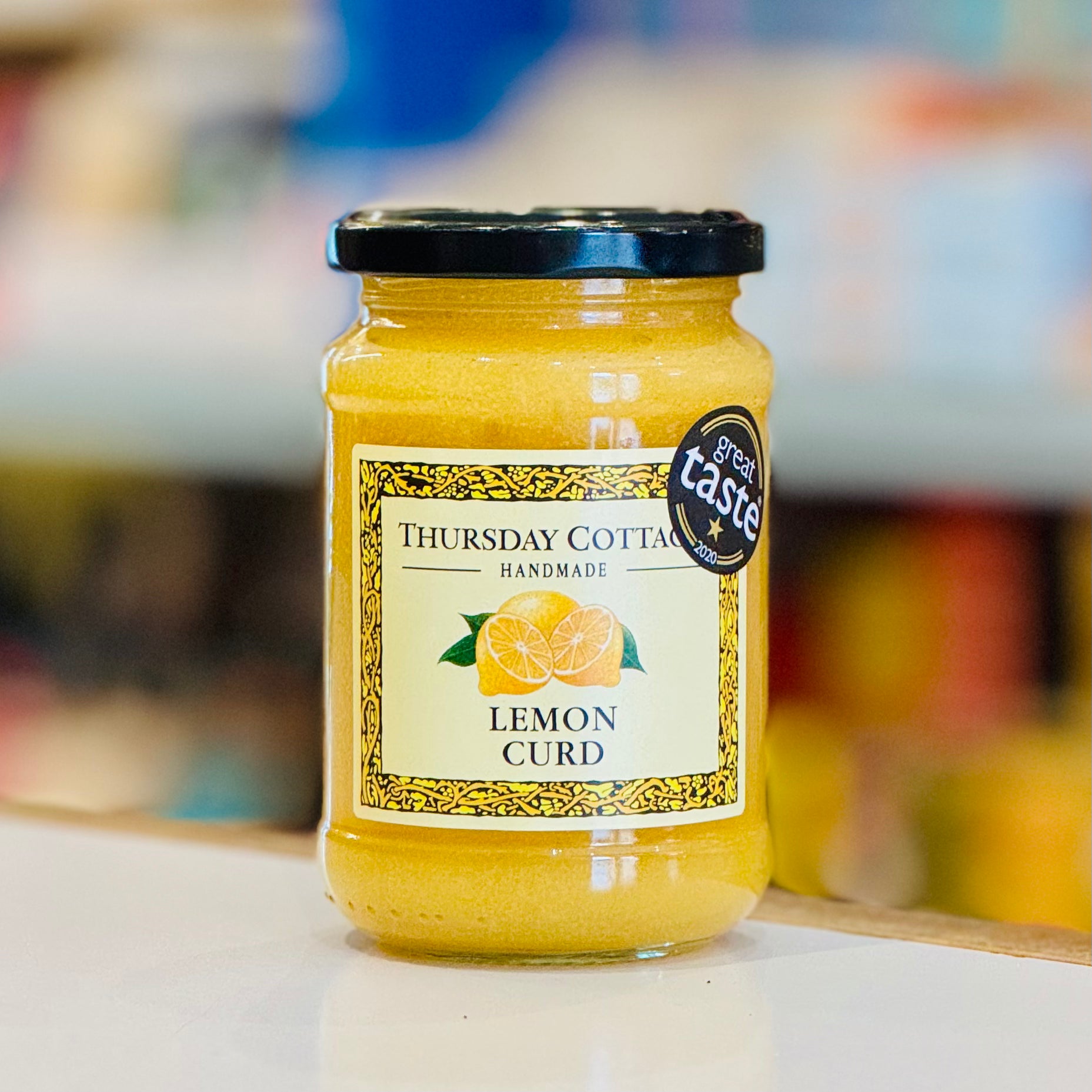 Jar of Thursday Cottages Lemon Curd with a 'Great Taste' award label on a blurred background