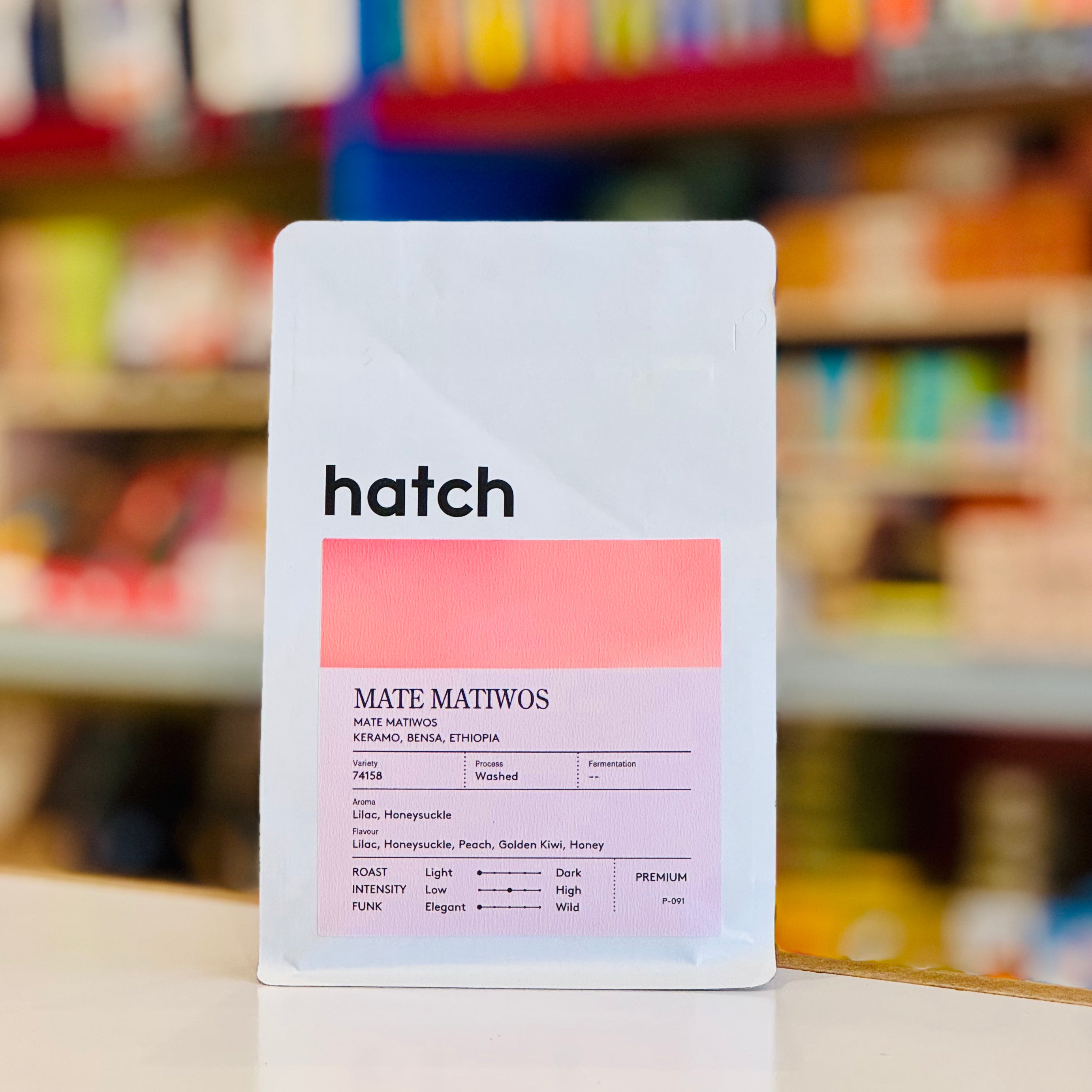 Hatch coffee package with a colorful label on a blurred store shelf background