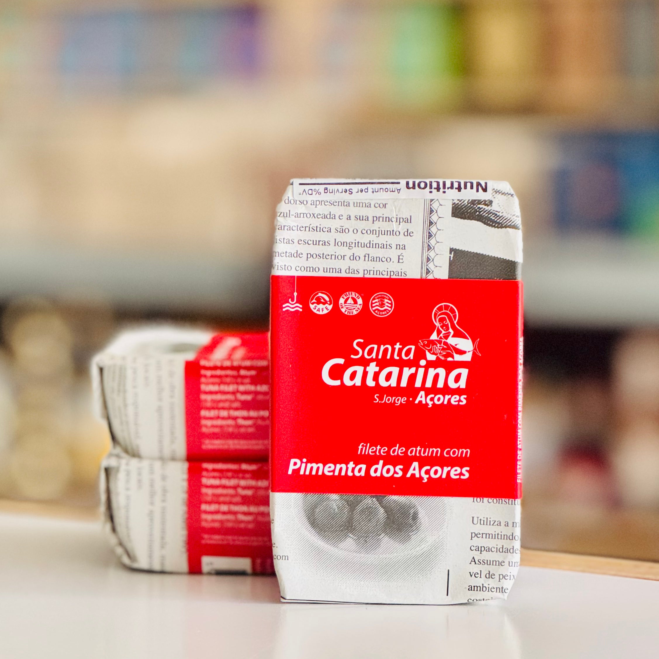 Packaged can wrapped in newprint with a red band with 'Santa Catarina' branding on a blurred background
