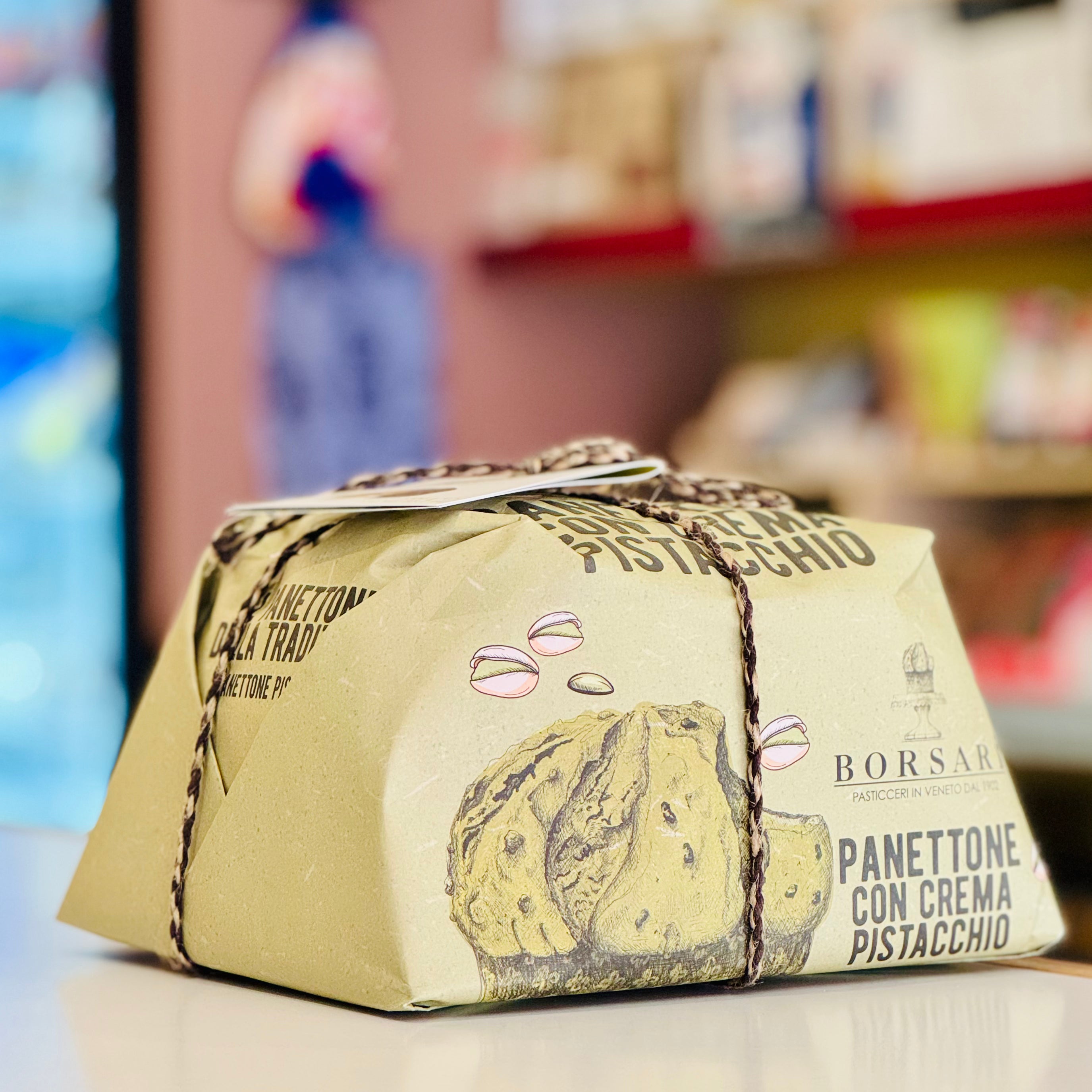 Packaged panettone with cream pistachio flavor on a blurred store shelf background