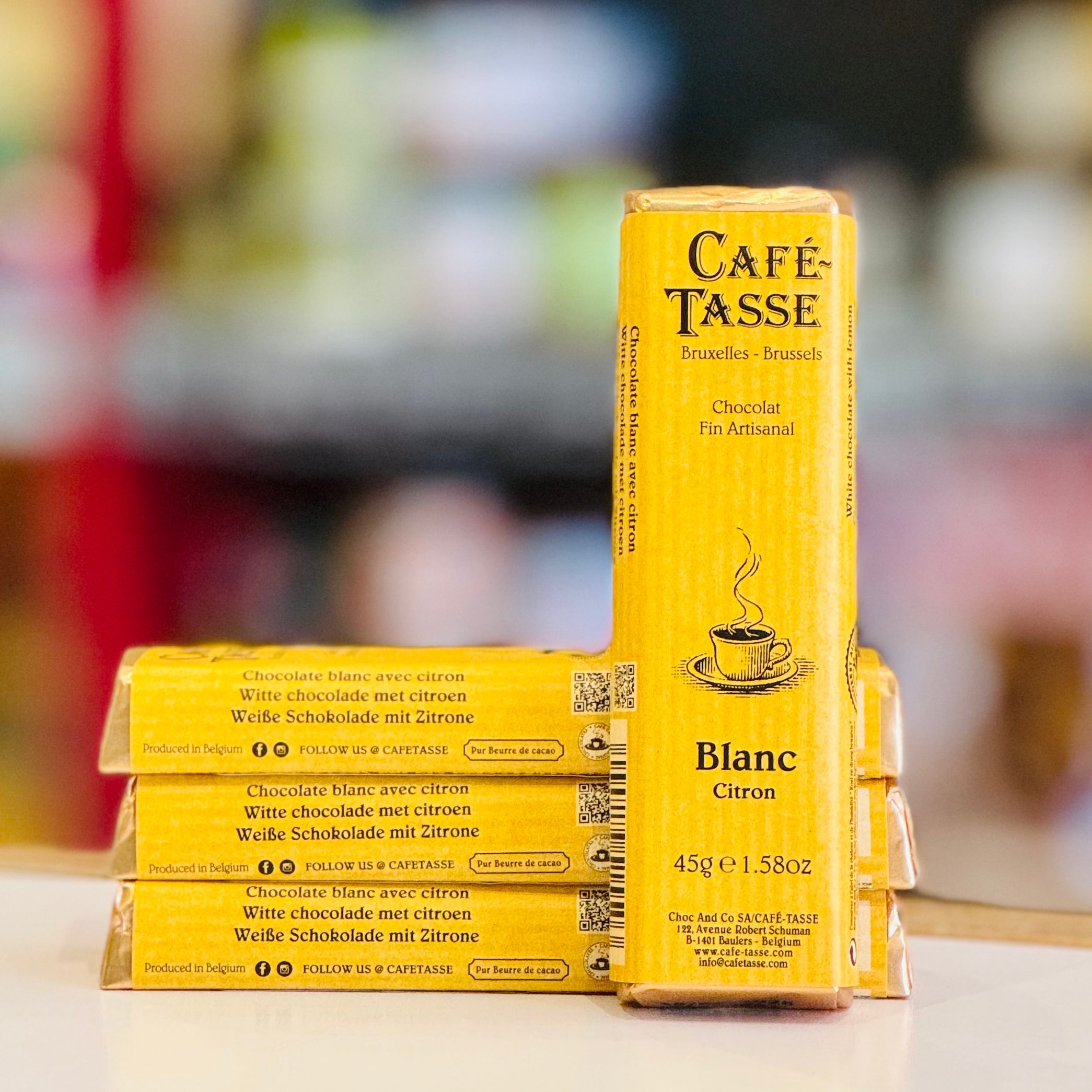 Yellow packaging of Café Tasse Blanc Citron chocolate bars on a blurred background