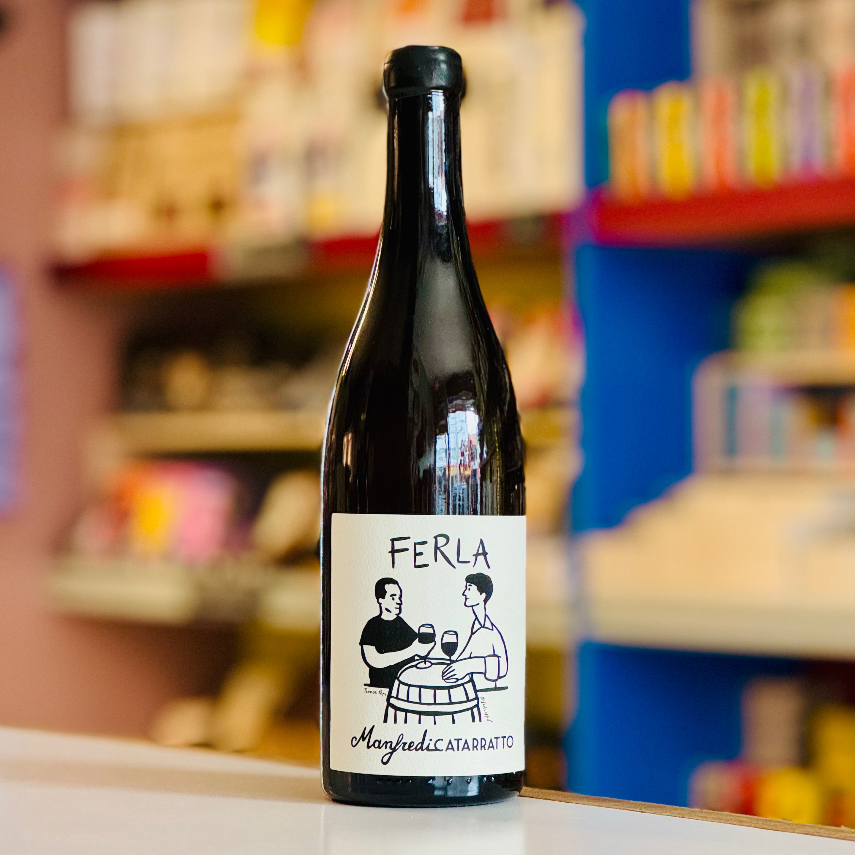 Bottle of Ferla wine with a label featuring two people at a table, on a shelf with blurred background.