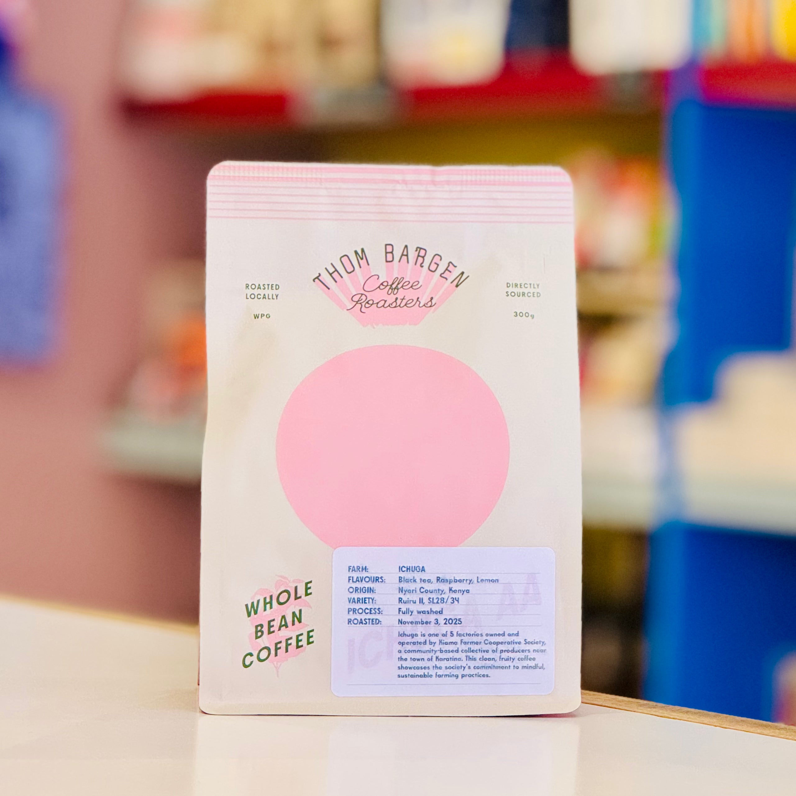 Coffee bag with pink circle design on a blurred store shelf background