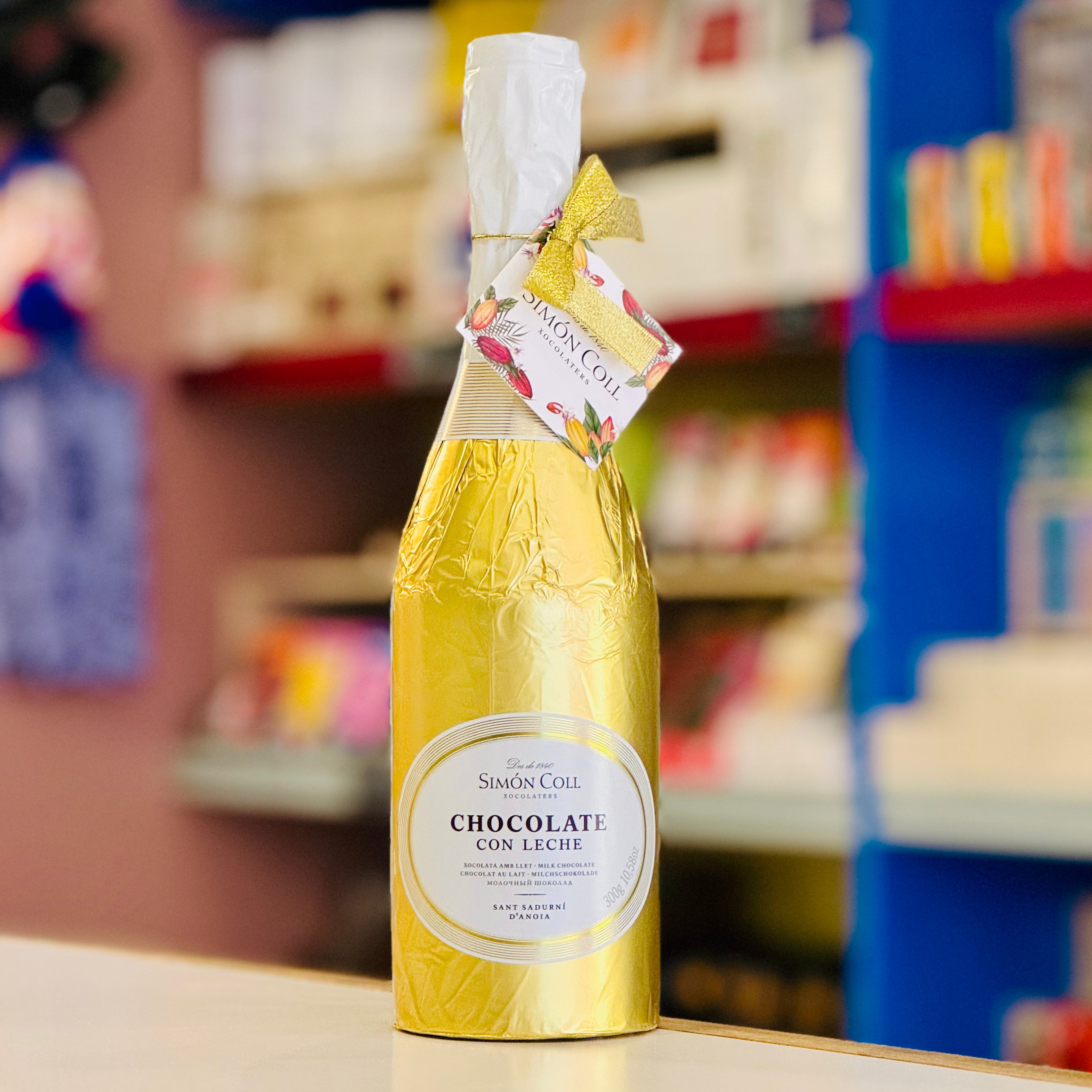 Yellow bottle of 'Chocolate con Leche' by Simon Coll on a shelf with a blurred store background