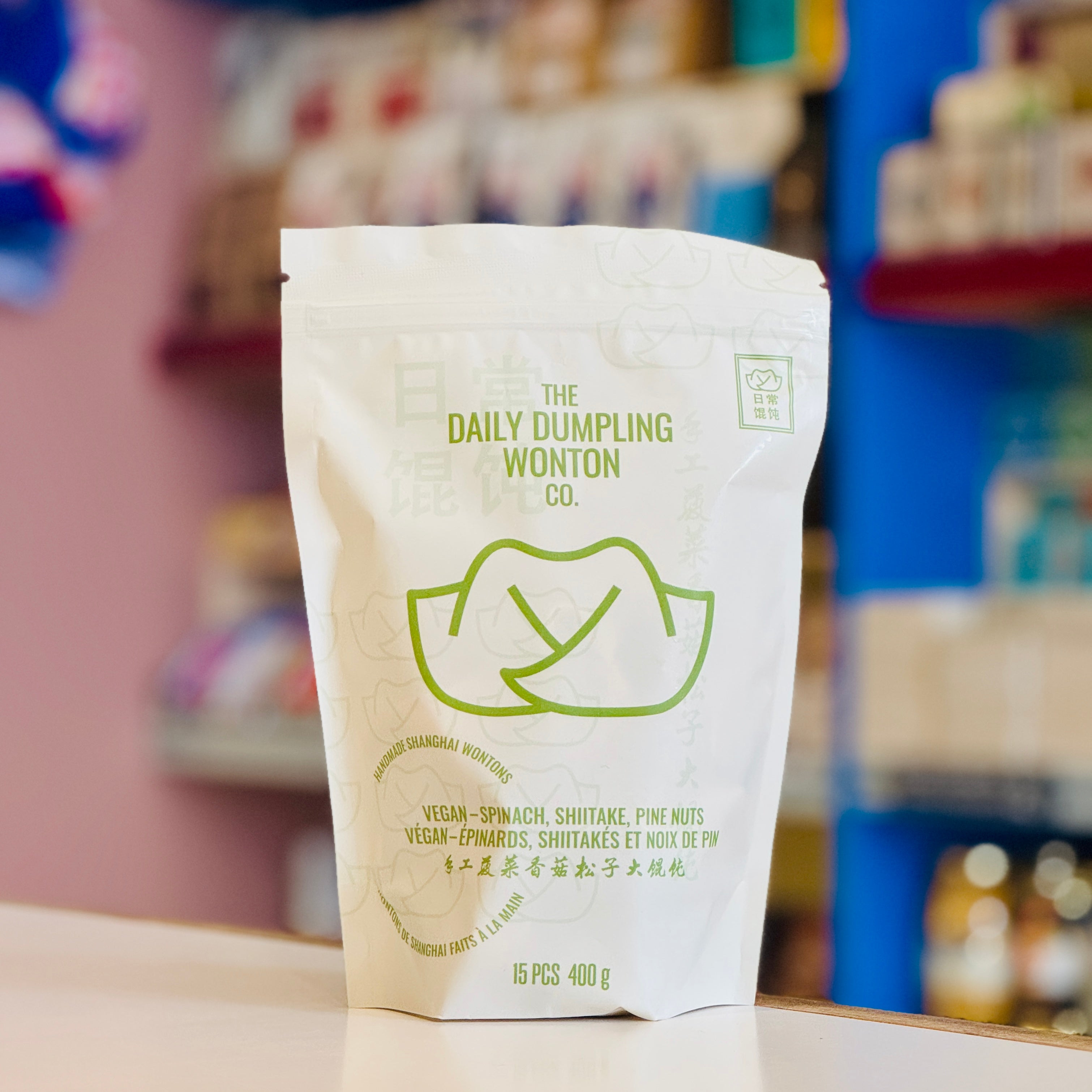 Packaging of The Daily Dumpling Wonton Co. on a blurred store shelf background
