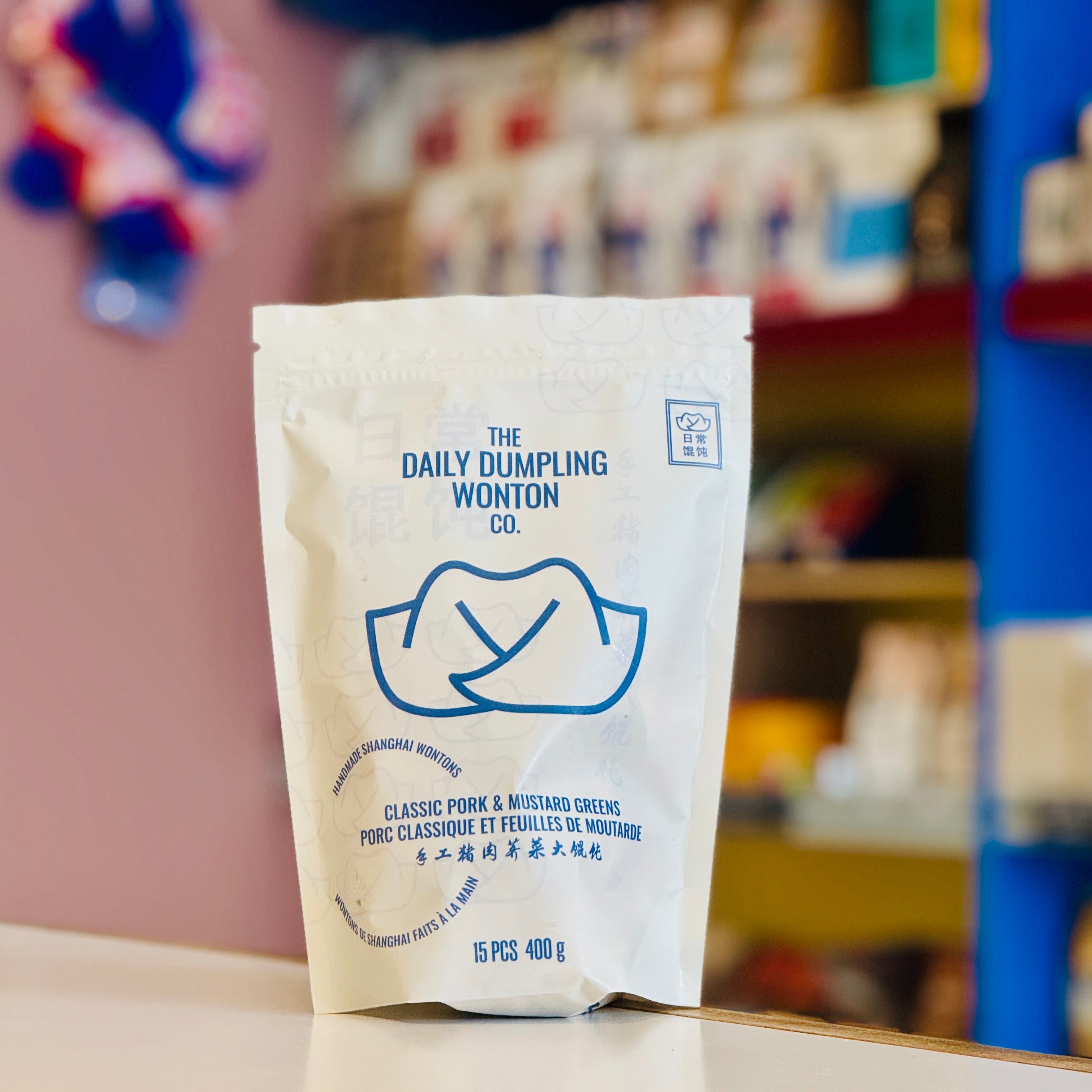 Packaged product from The Daily Dumpling Wonton Co. on a shelf with blurred background