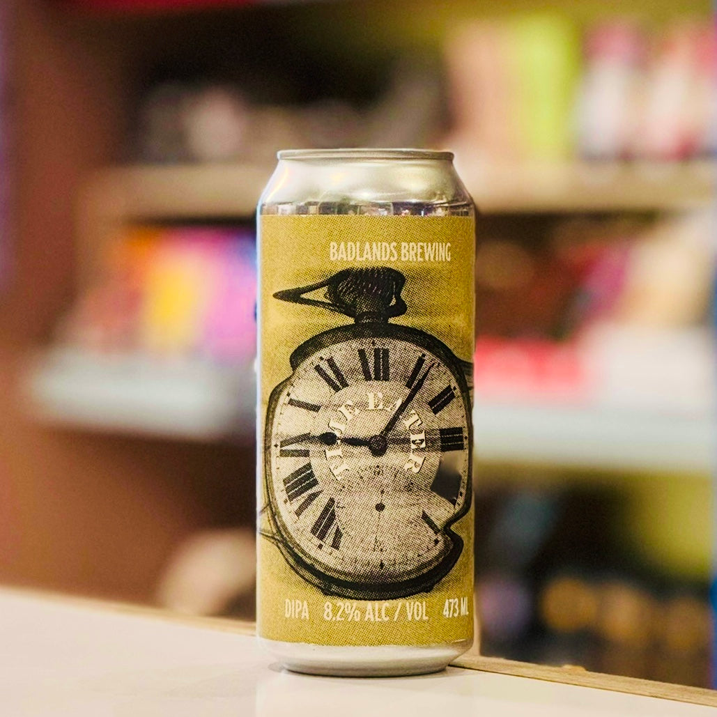 Beer can with clock design and 'Badlands Brewing' branding on a blurred background