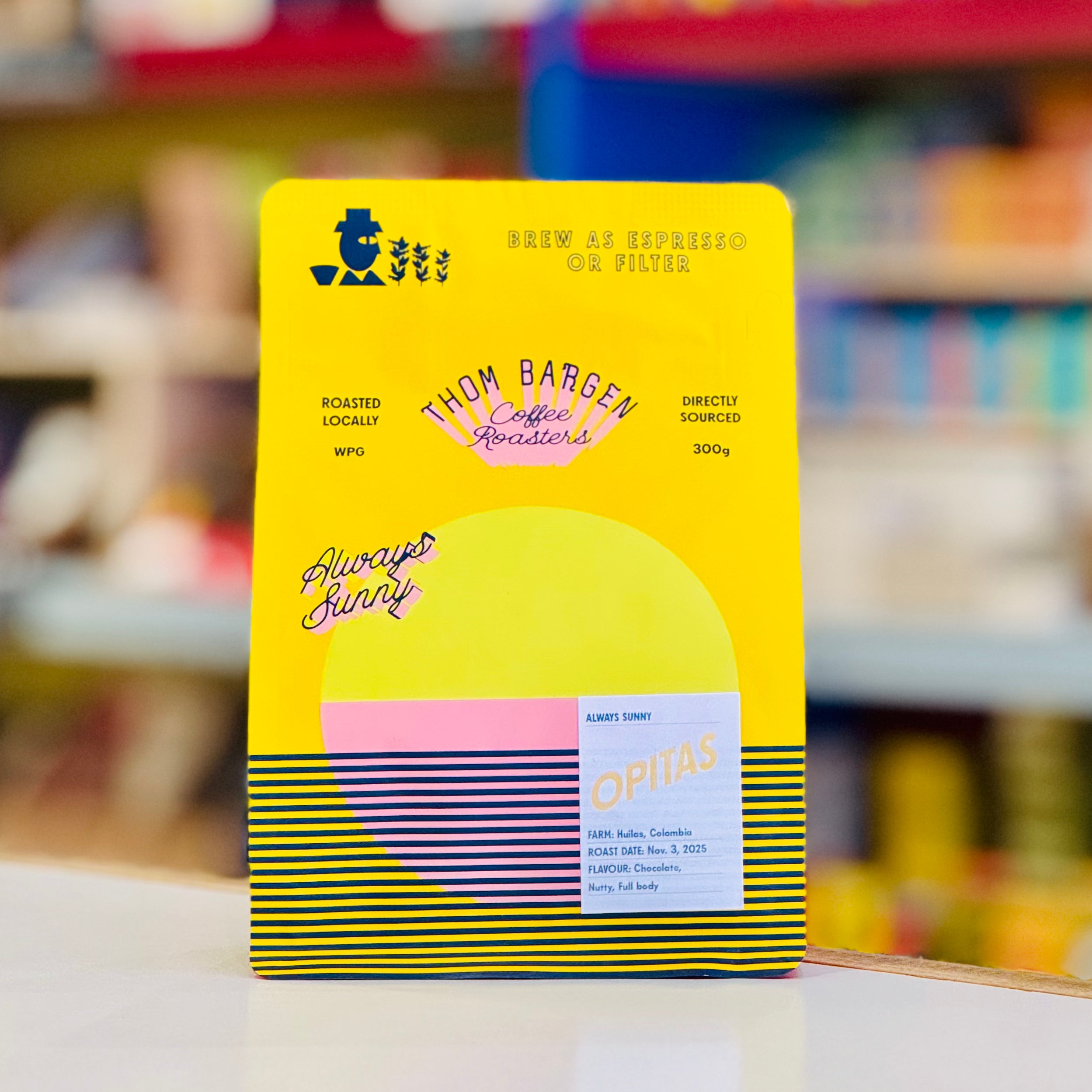 Colorful coffee packaging with branding on a blurred store shelf background