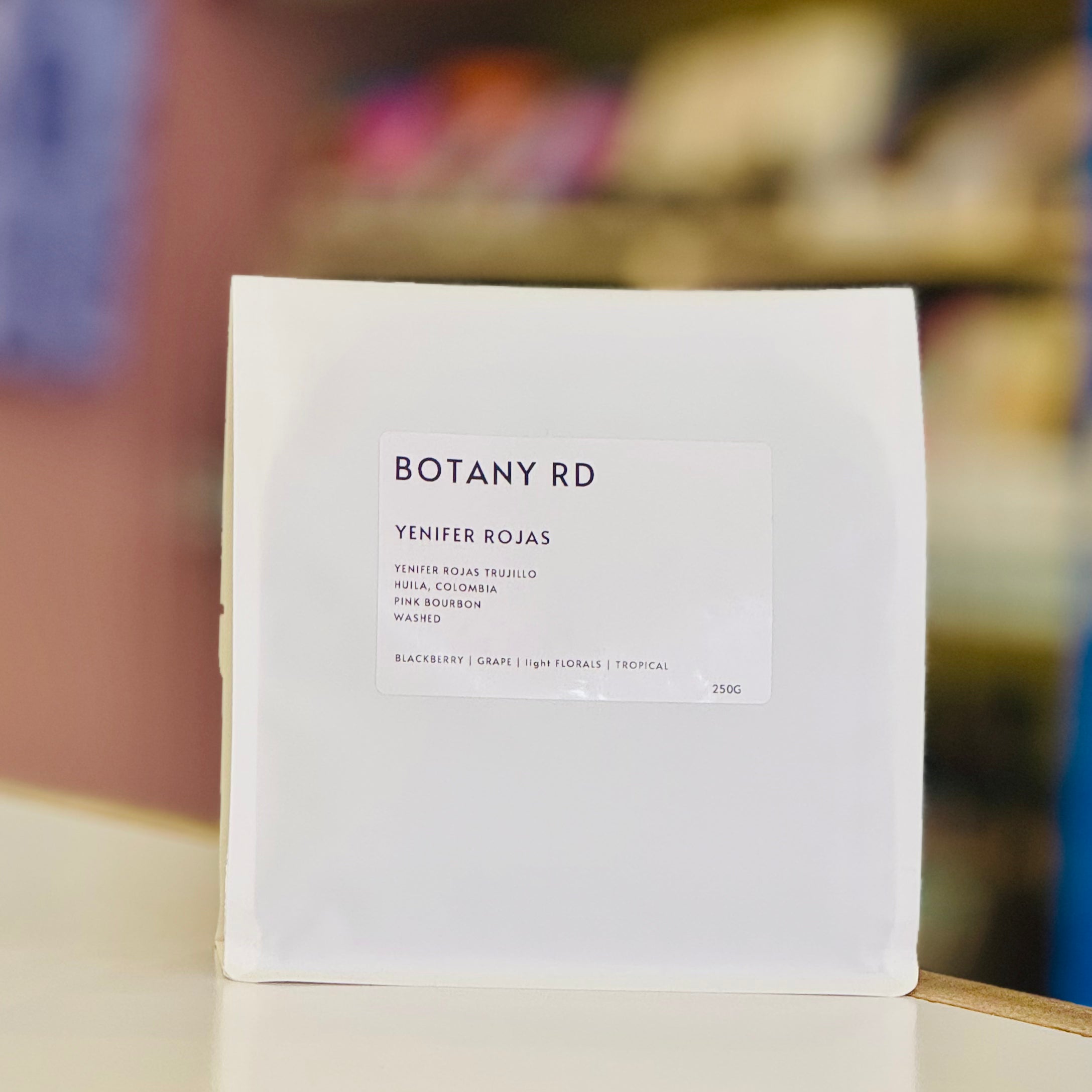 White bag of coffee with 'BOTANY RD' and 'Yenifer Rojas' on a blurred background