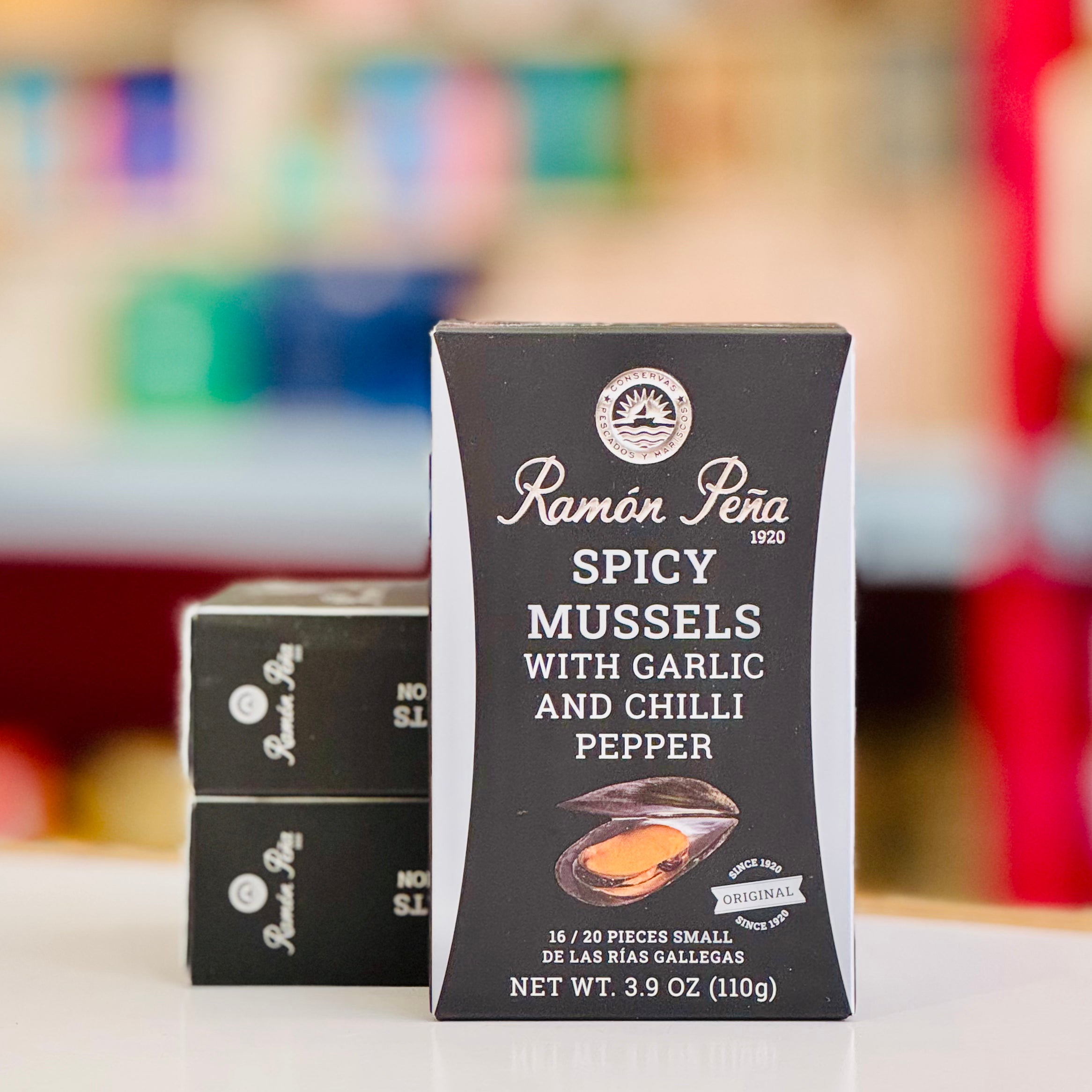 Ramon Pera spicy mussels packaging with garlic and chilli pepper on a blurred background
