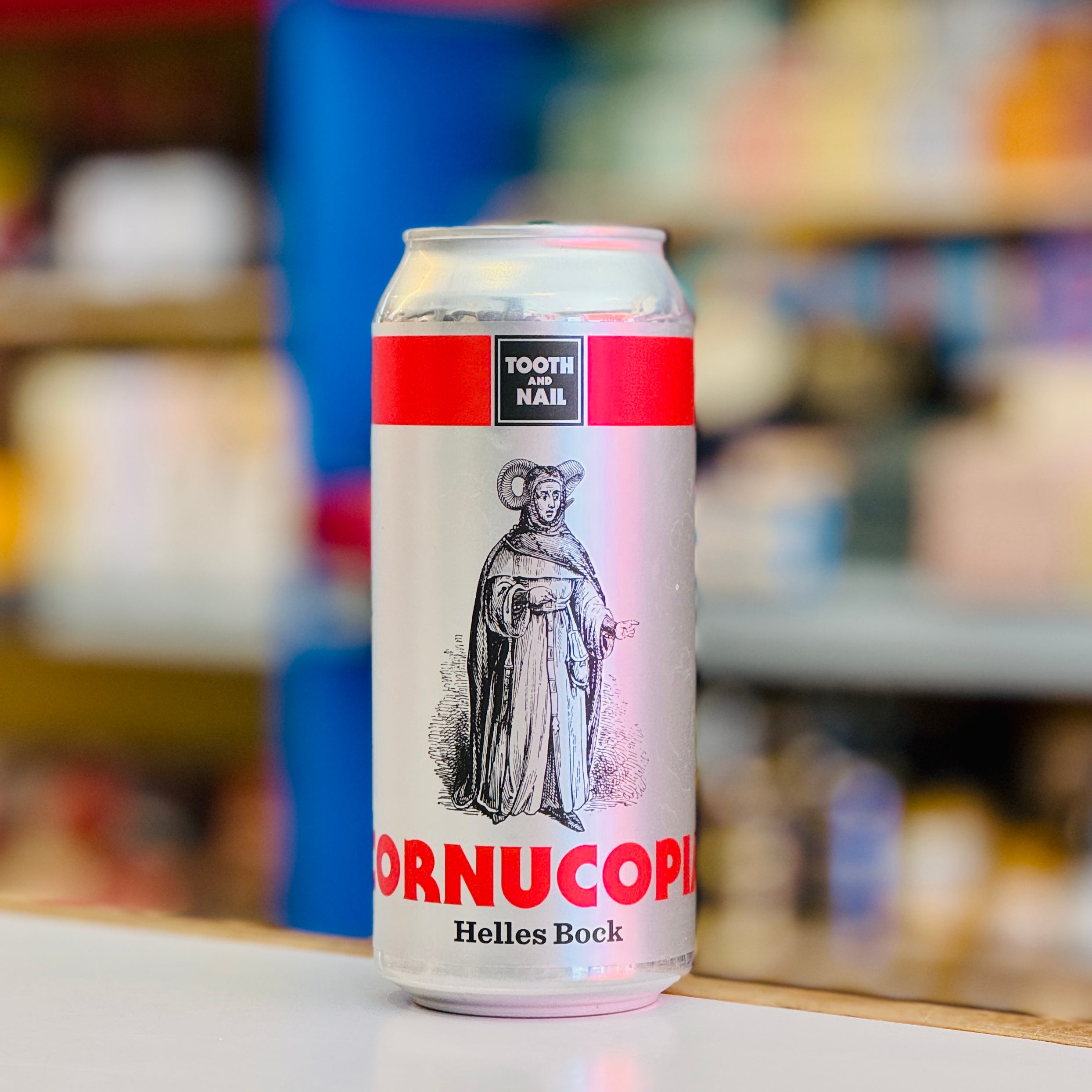 Beer can labeled 'ORNUCOPI' with a blurred store shelf background