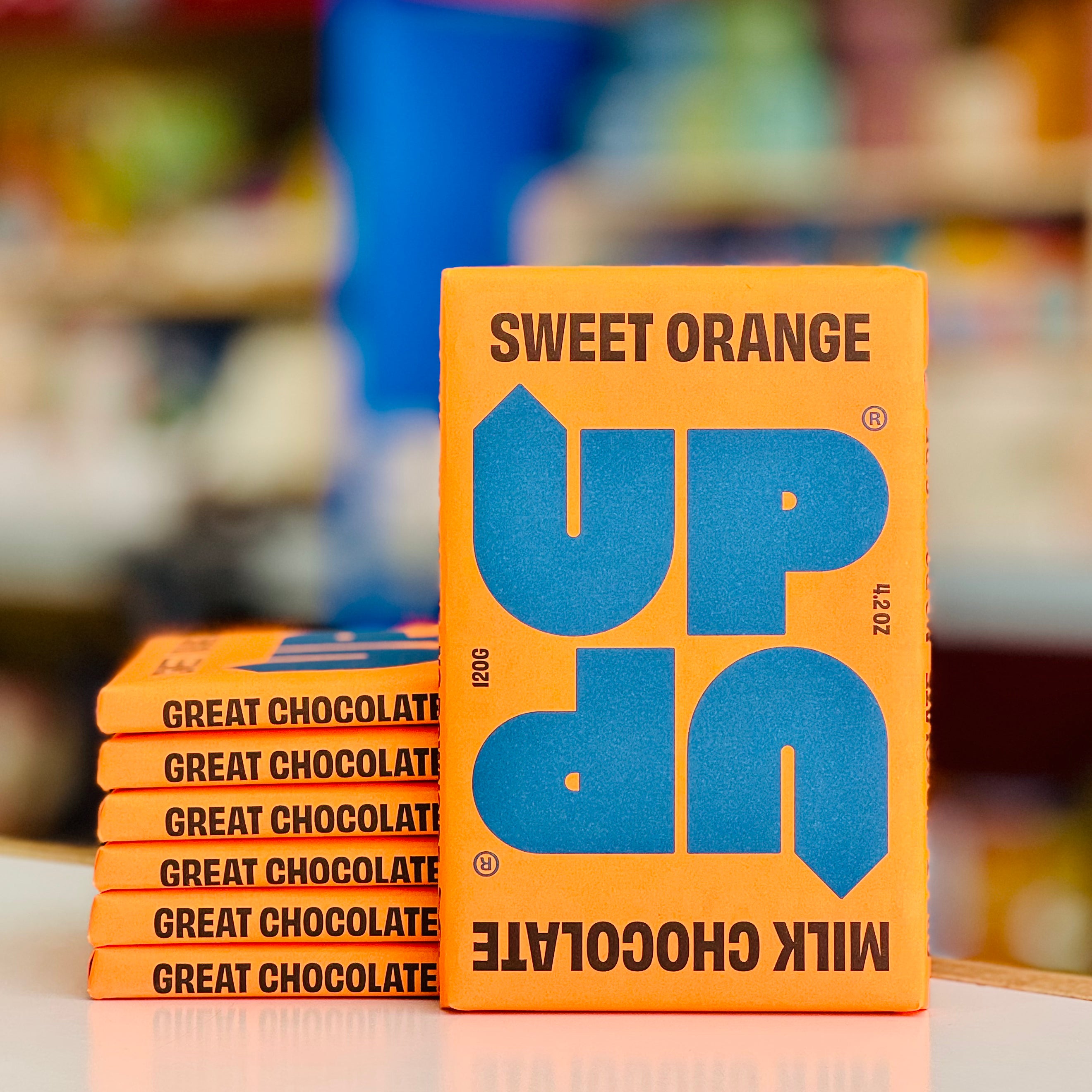 Stack of 'UP' chocolate boxes with a blurred store background